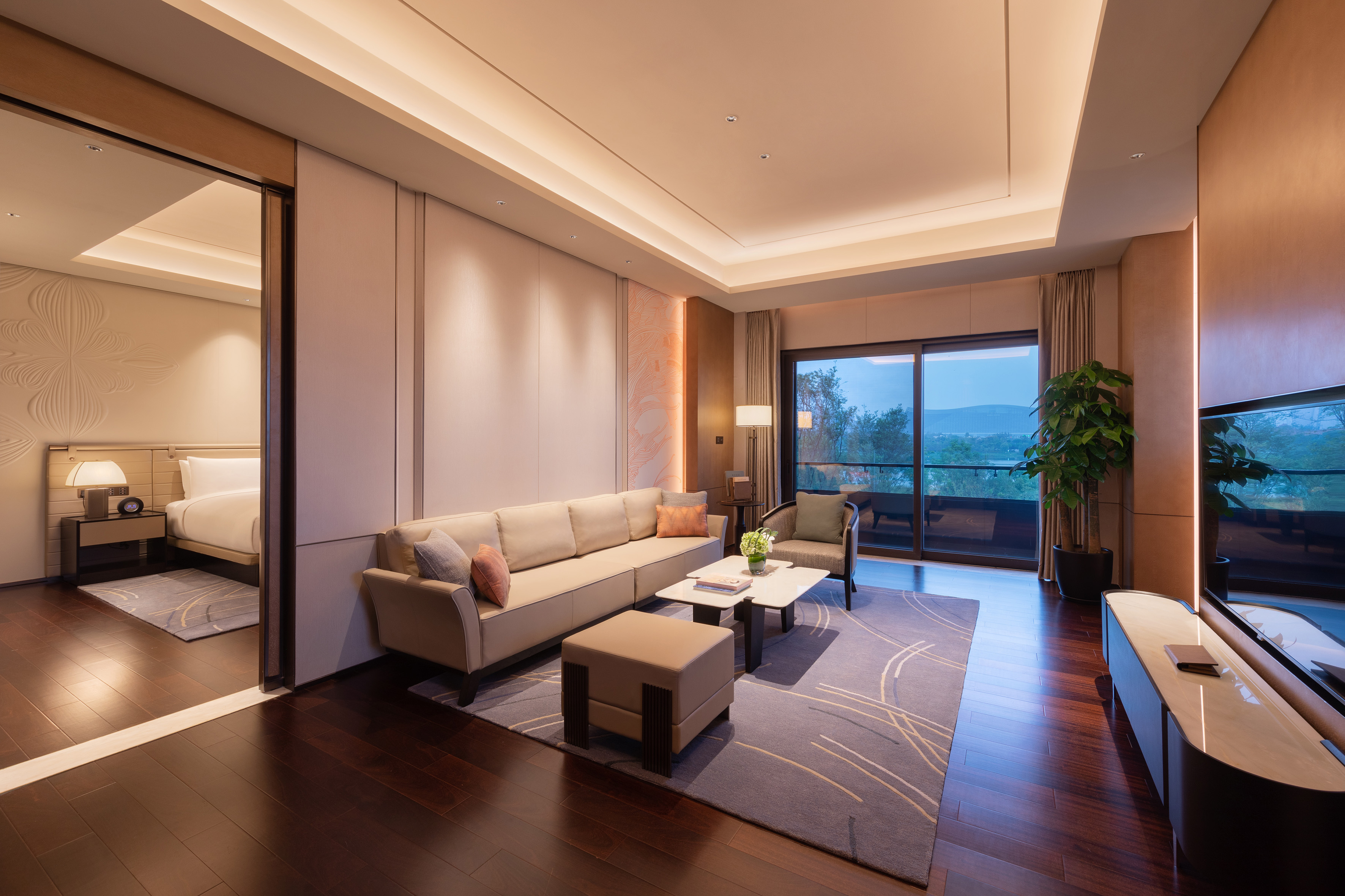 Elegant hotel suite living room with sofa, balcony, and adjoining bedroom.