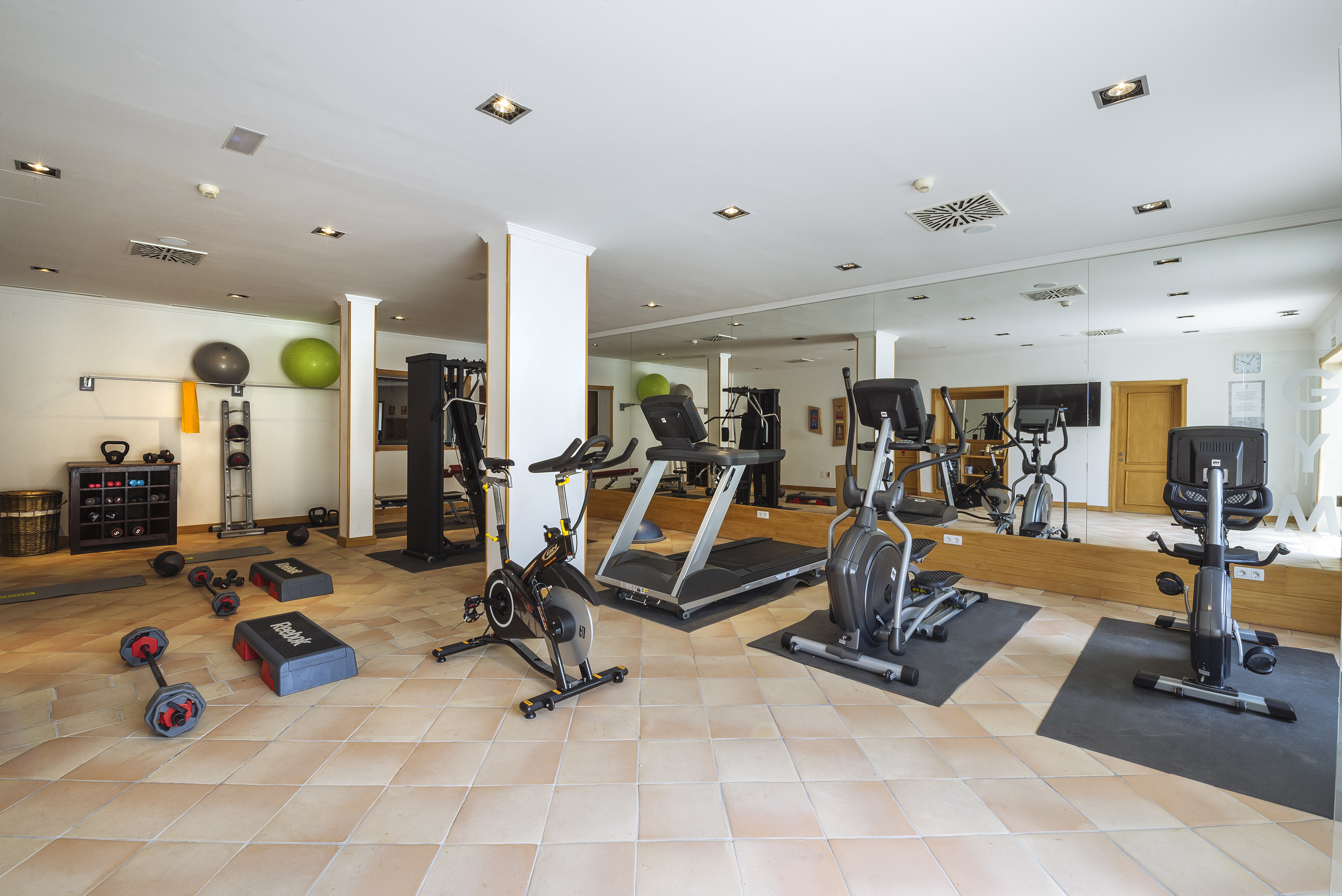 Bright fitness room with diverse cardio and weight training equipment.