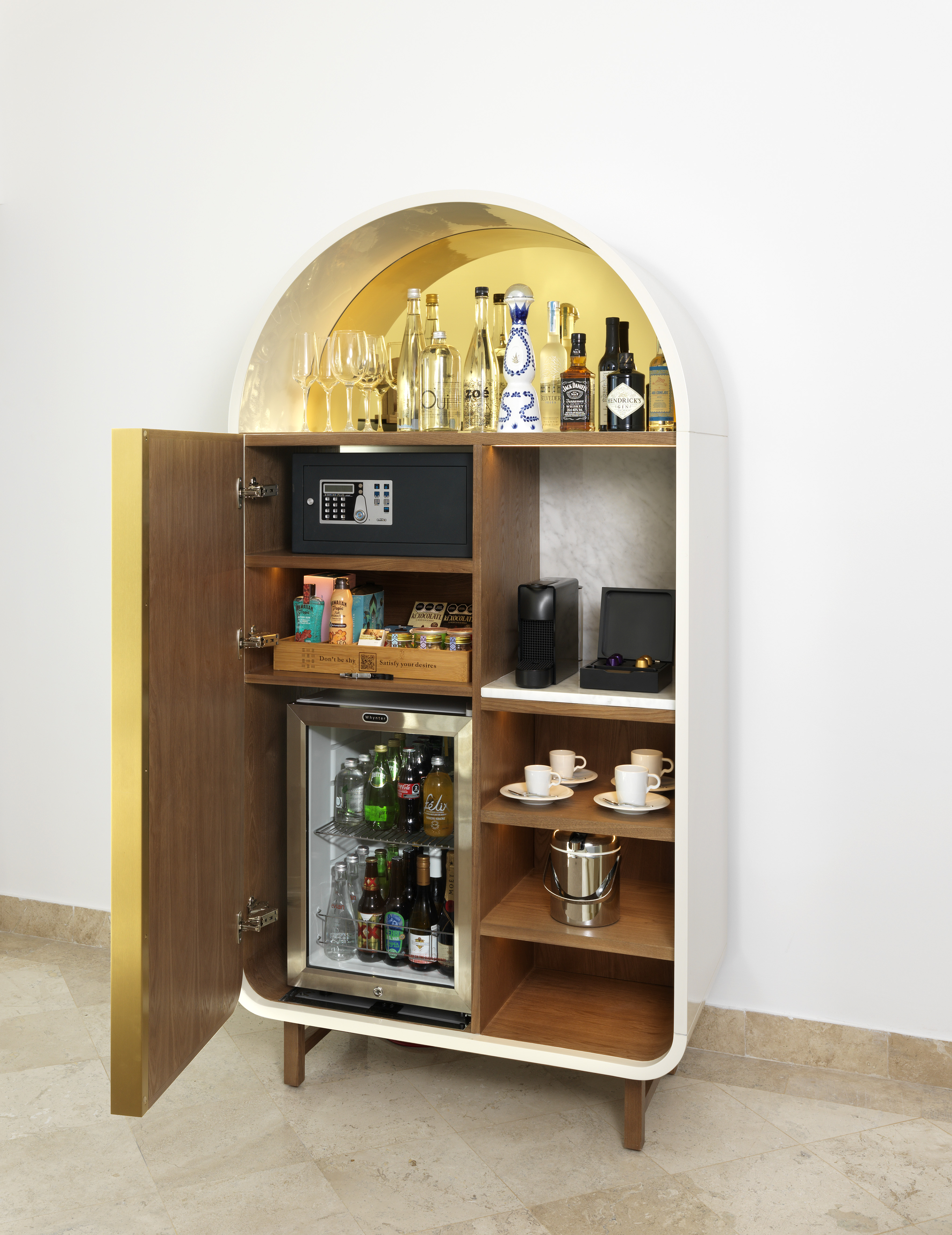 Minibar de hotel moderno con bebidas variadas, máquina de café y caja fuerte.