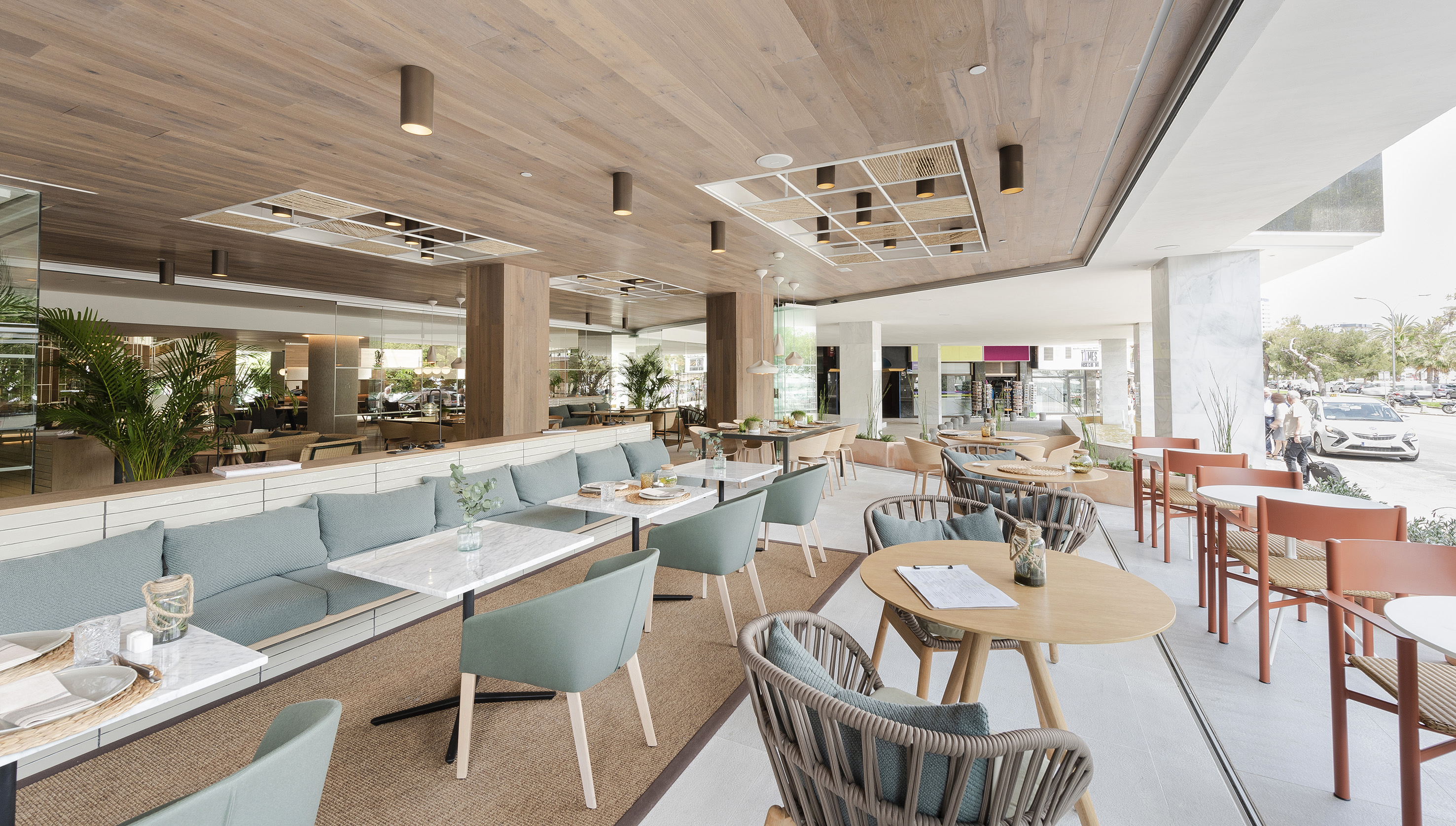 Modern restaurant with indoor/outdoor dining, wood ceiling, and green seating.