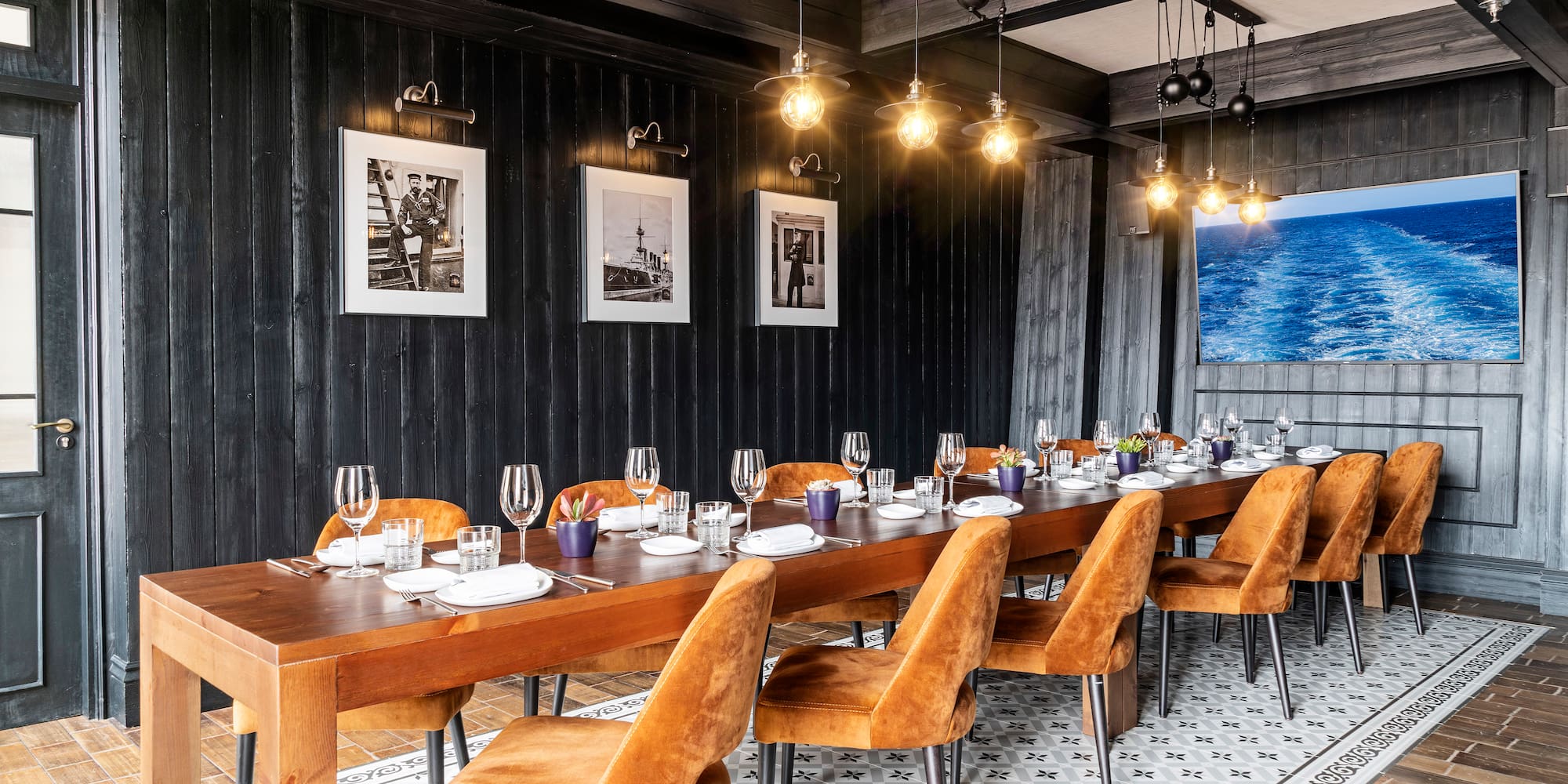 a long table with plates and glasses in a room with black walls