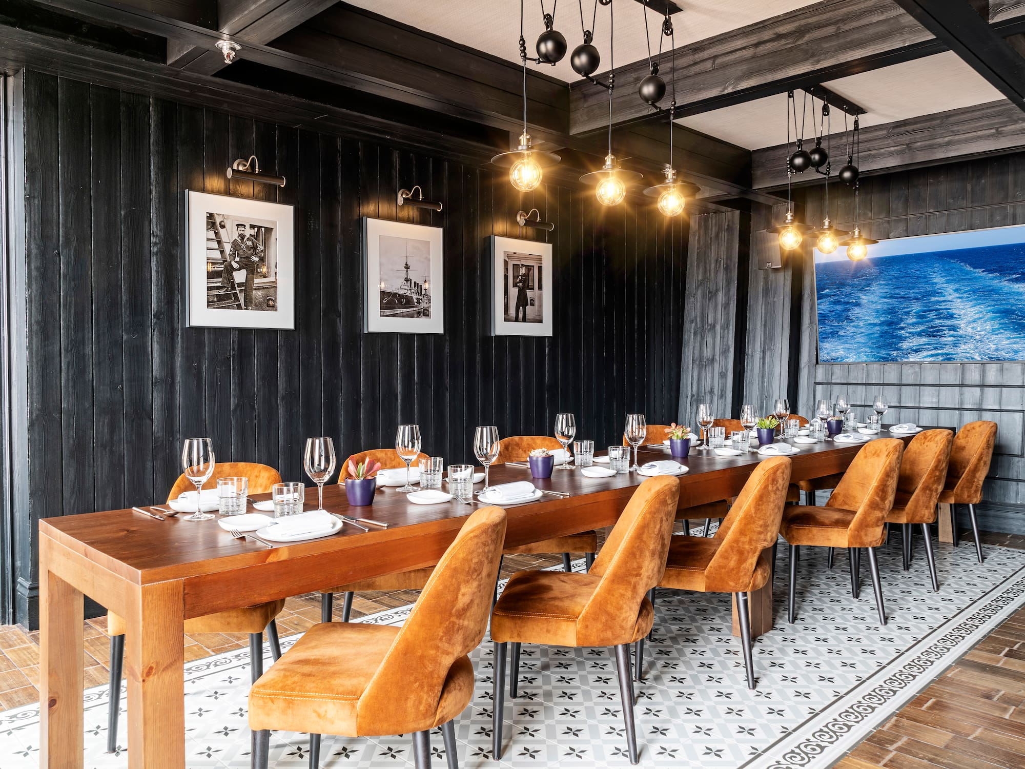 a long table with plates and glasses in a room with black walls