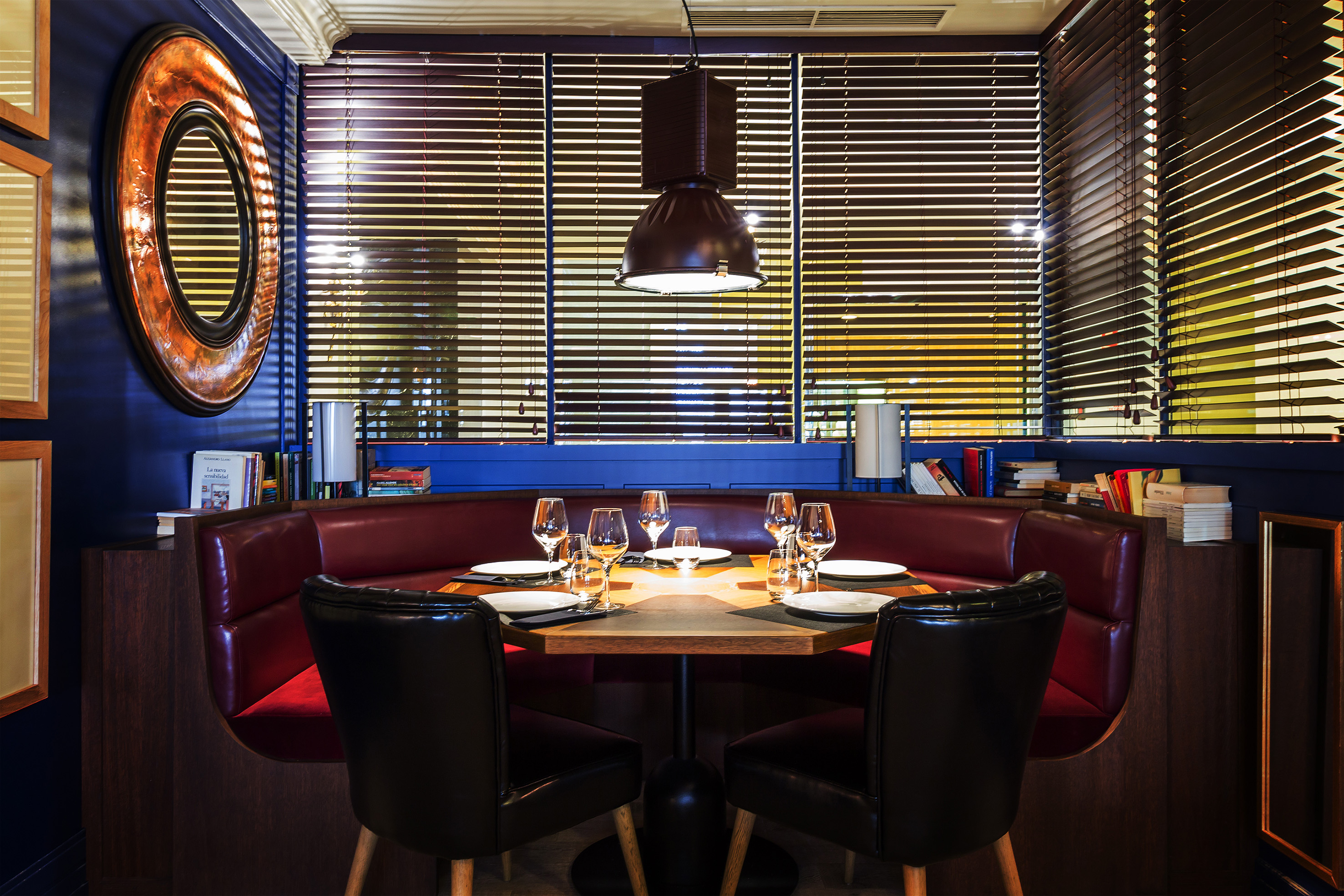 Restaurant booth with red leather seating, octagonal table, and blue walls.