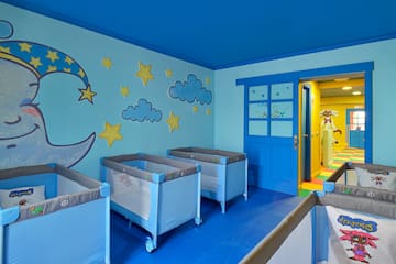 a room with cribs and clouds and stars on the wall