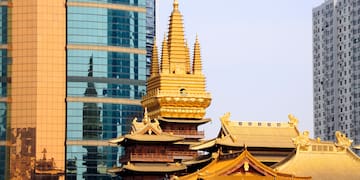 a gold pagoda with a tall tower in front of a glass building