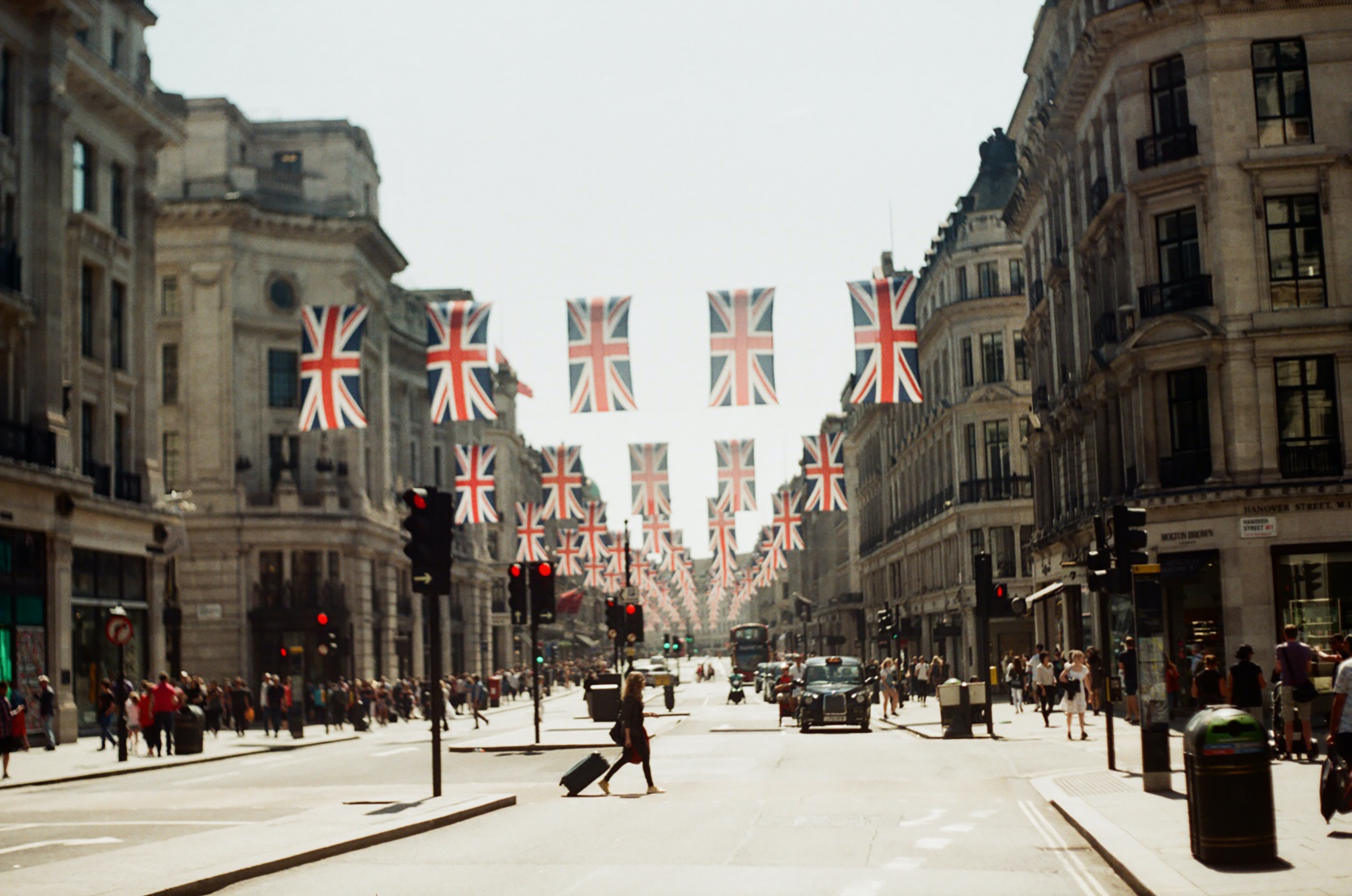 Calle de Londres decorada con banderas Union Jack, peatones y taxis.