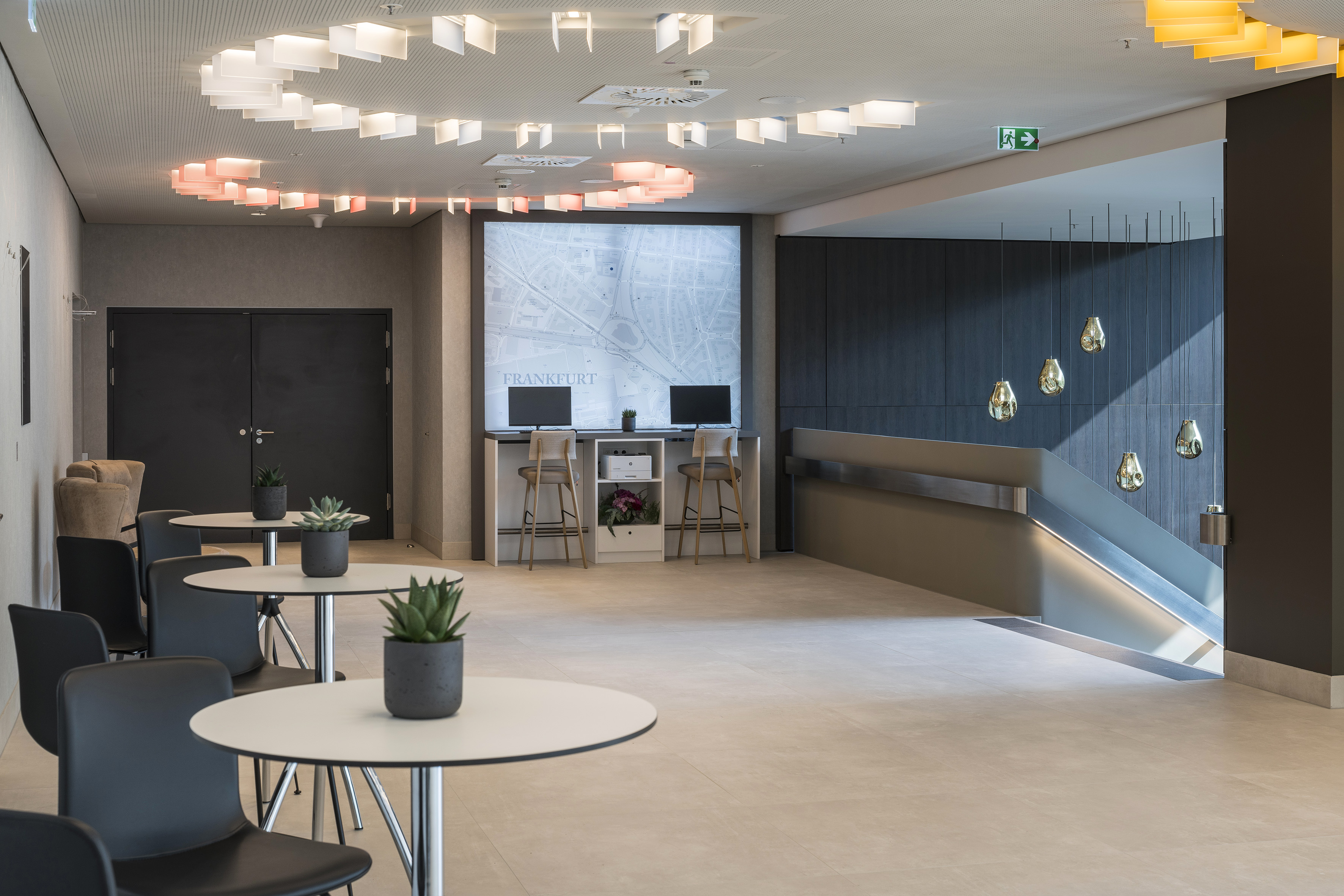 Modern lobby: Frankfurt map computer station, lounge seating, unique lighting.