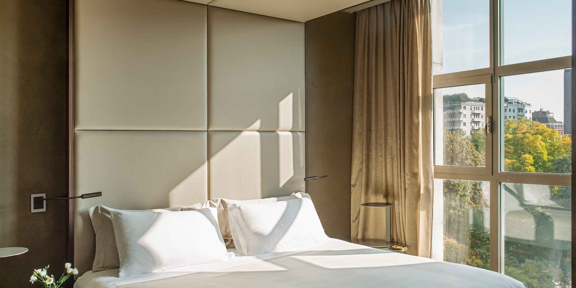 a bed with a white cover and pillows in a room with a window