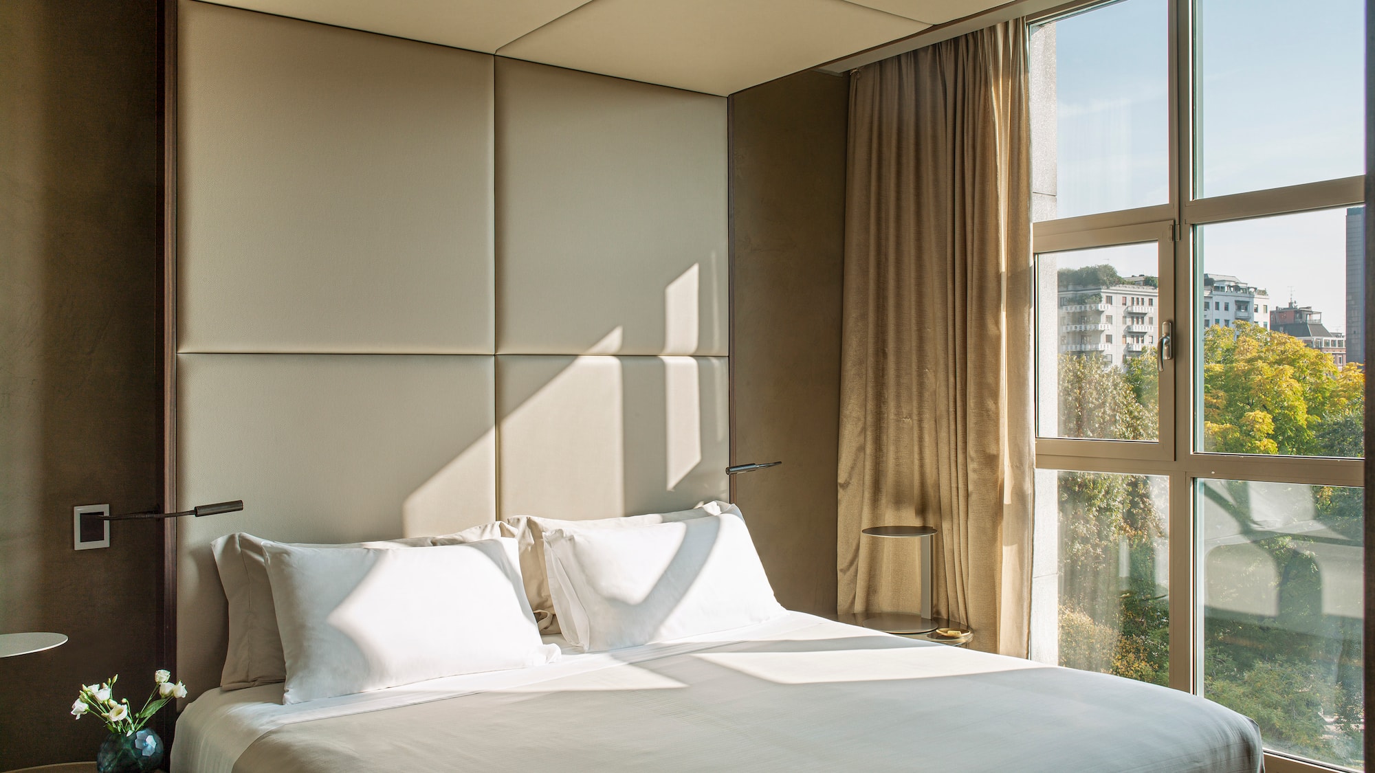 a bed with a white cover and pillows in a room with a window