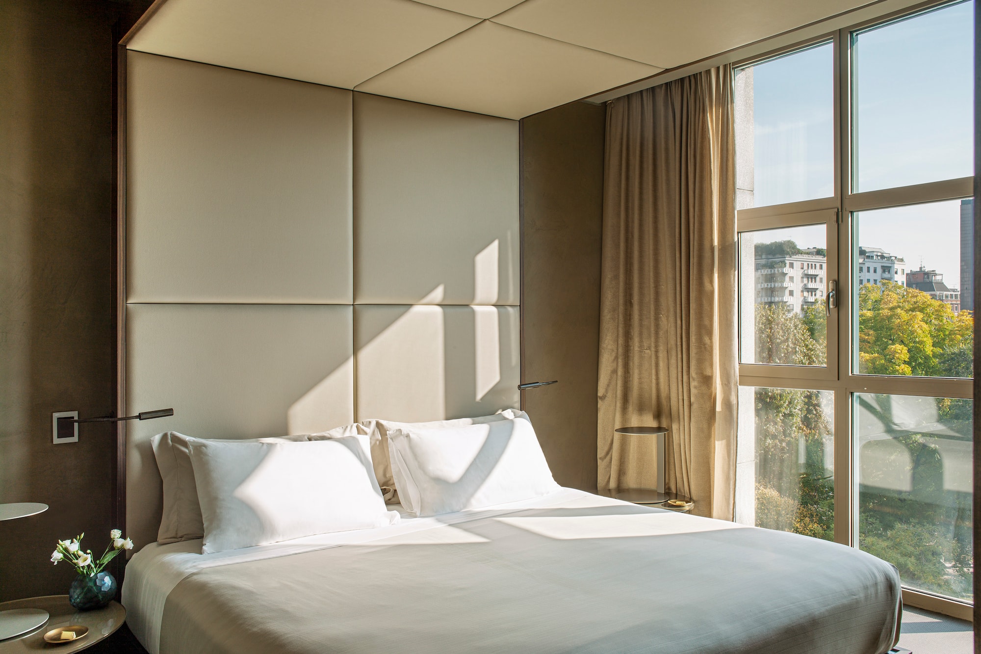 a bed with a white cover and pillows in a room with a window