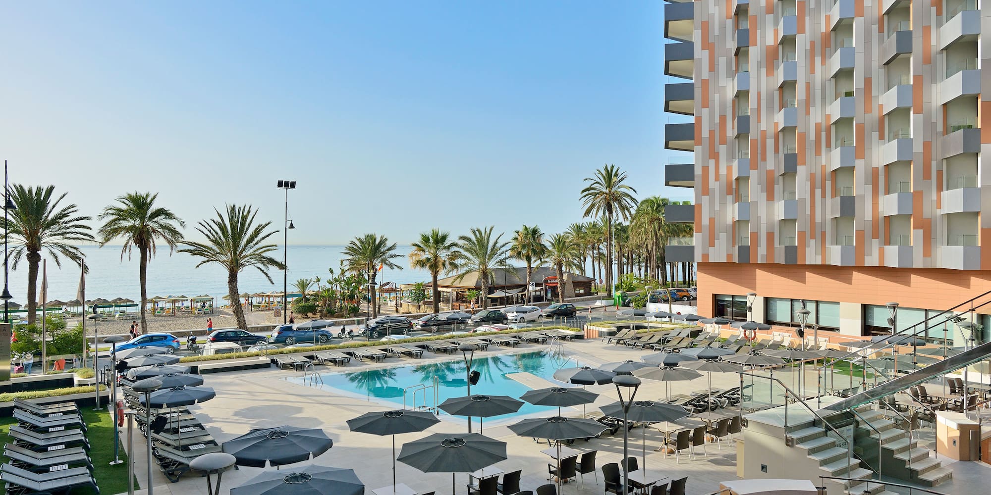 a pool with umbrellas and chairs by a building