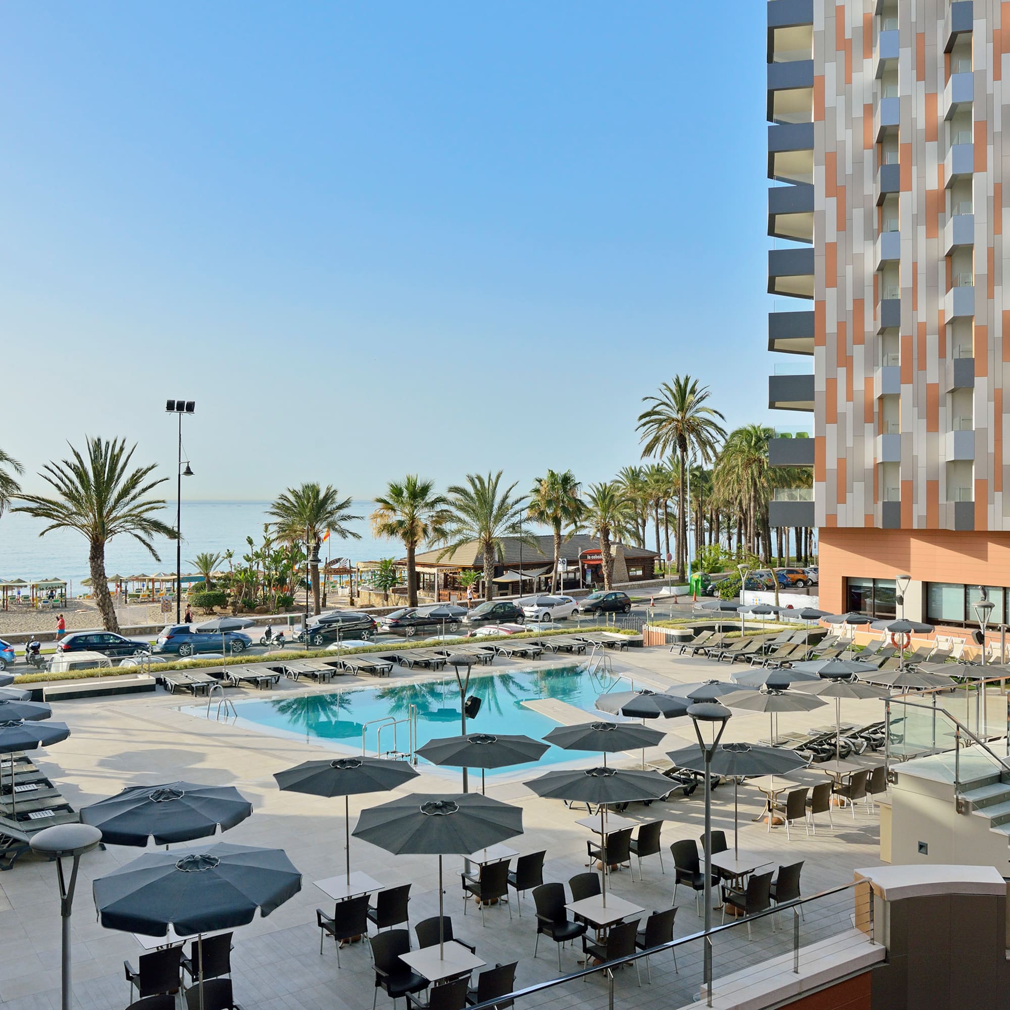 a pool with umbrellas and chairs by a building