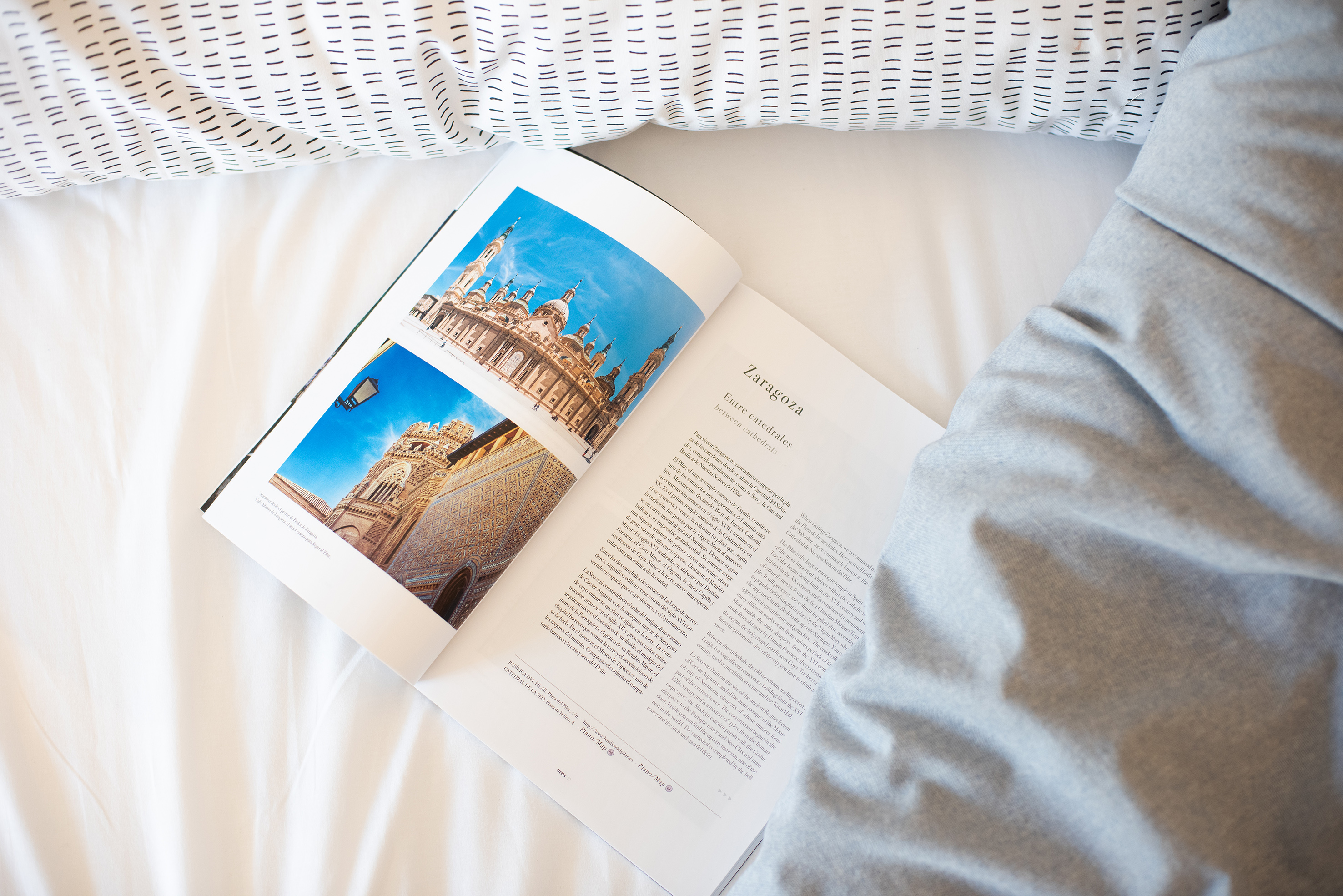 Zaragoza travel guide open to cathedral photos on a white bed.