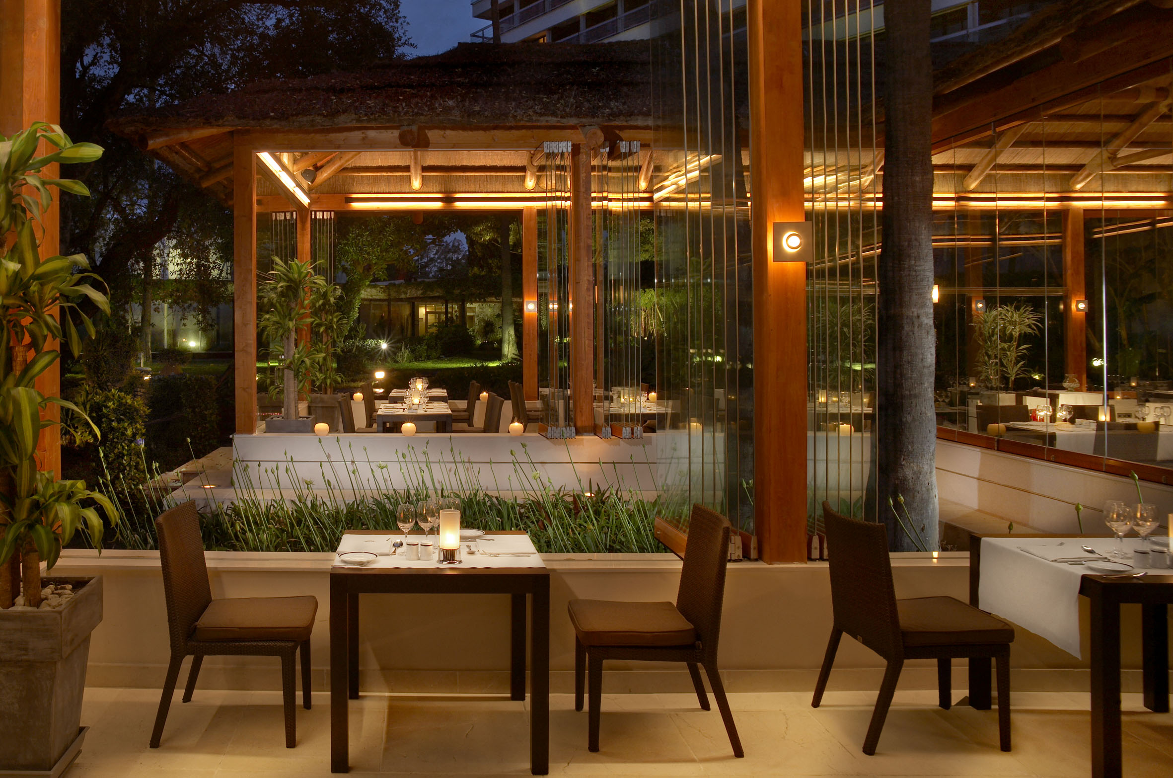 Elegant outdoor restaurant patio at night with ambient lighting and set tables.