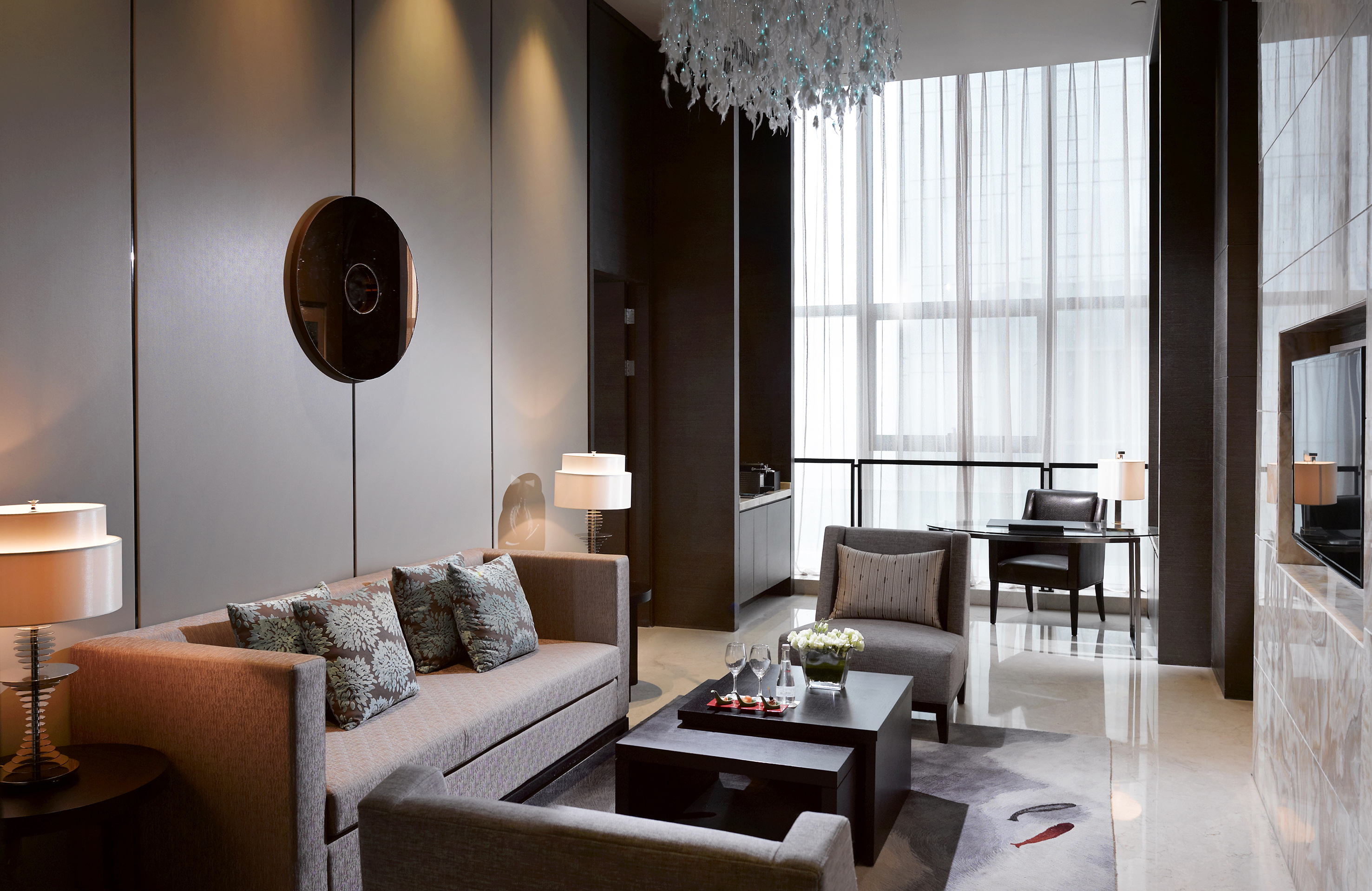 Luxury hotel suite living room with modern sofa, elegant decor, and bright window.