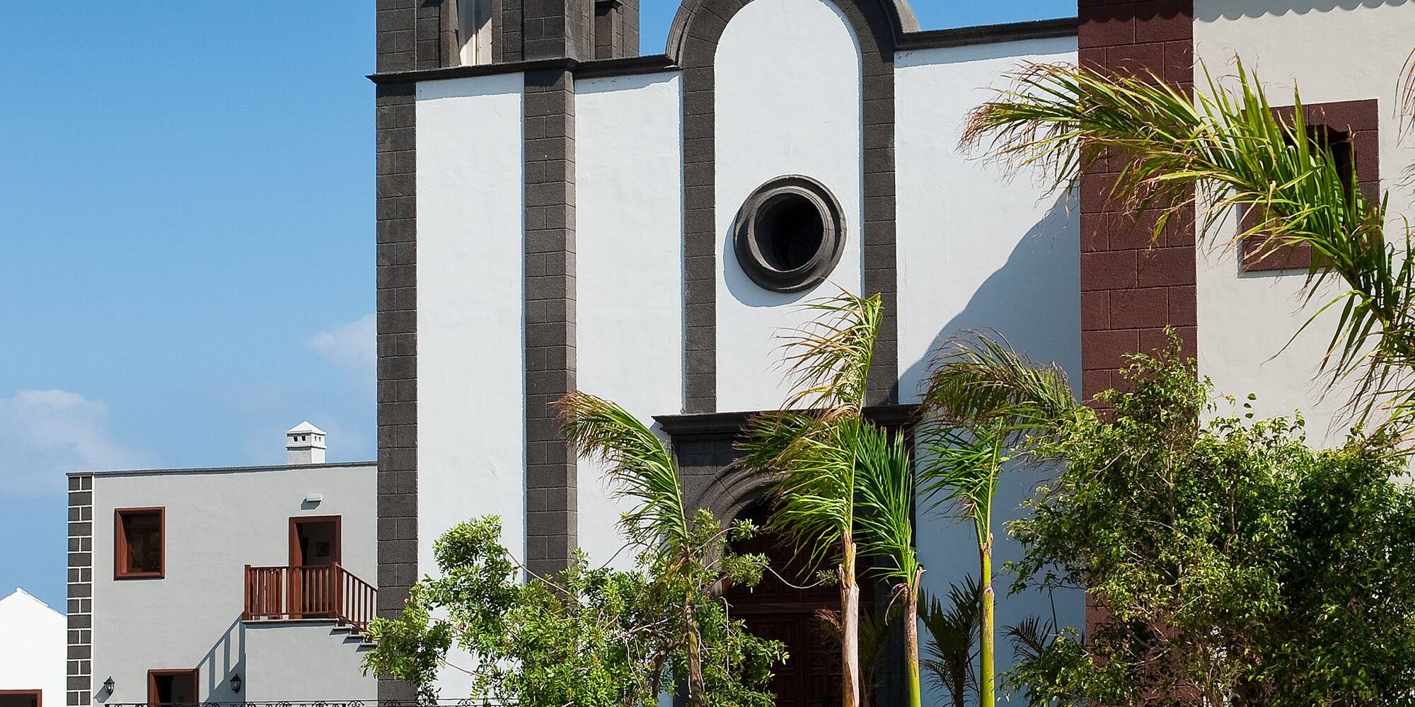 a white building with a tower and a flower bed