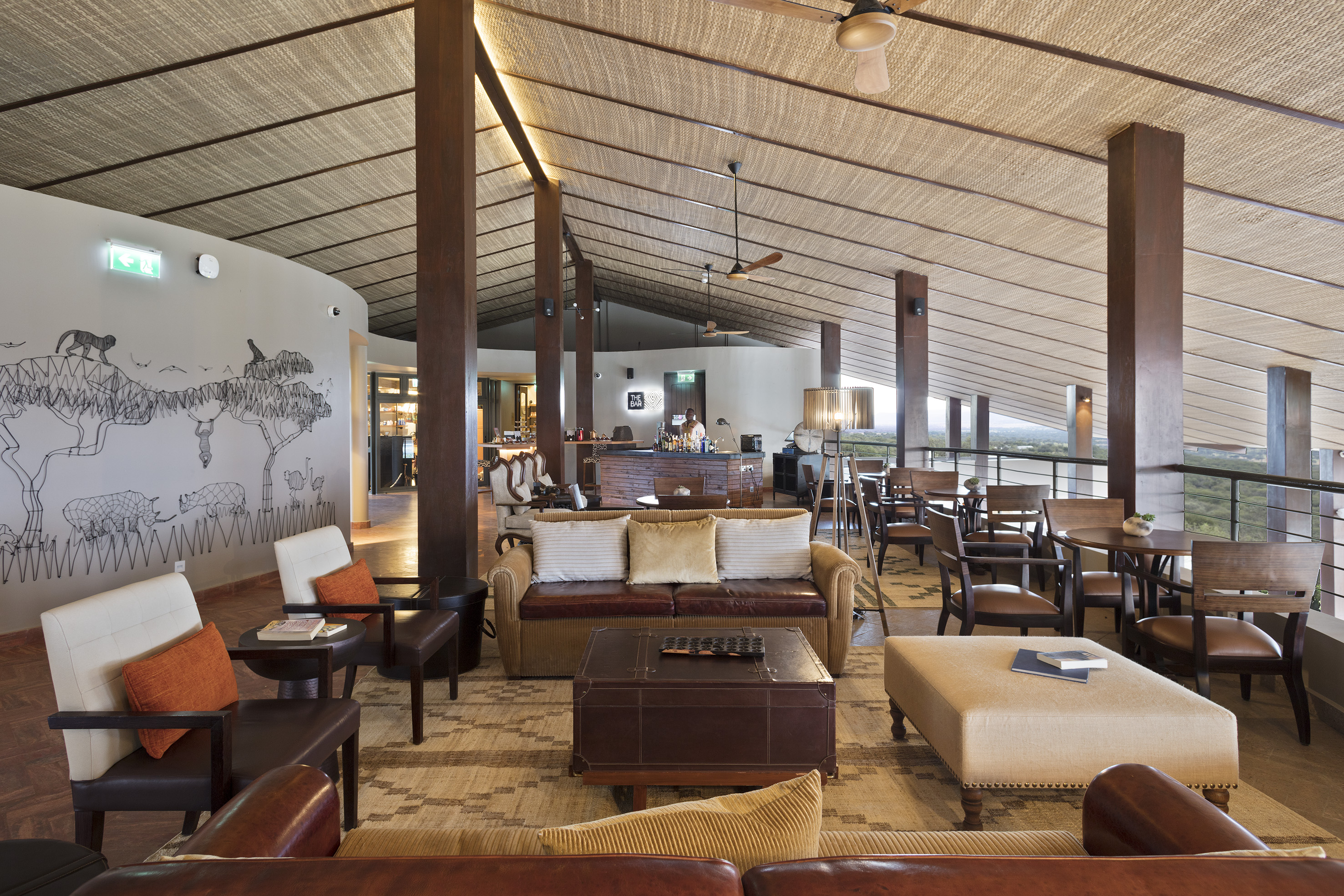 Spacious safari lodge lounge with rustic decor, bar, and animal mural.