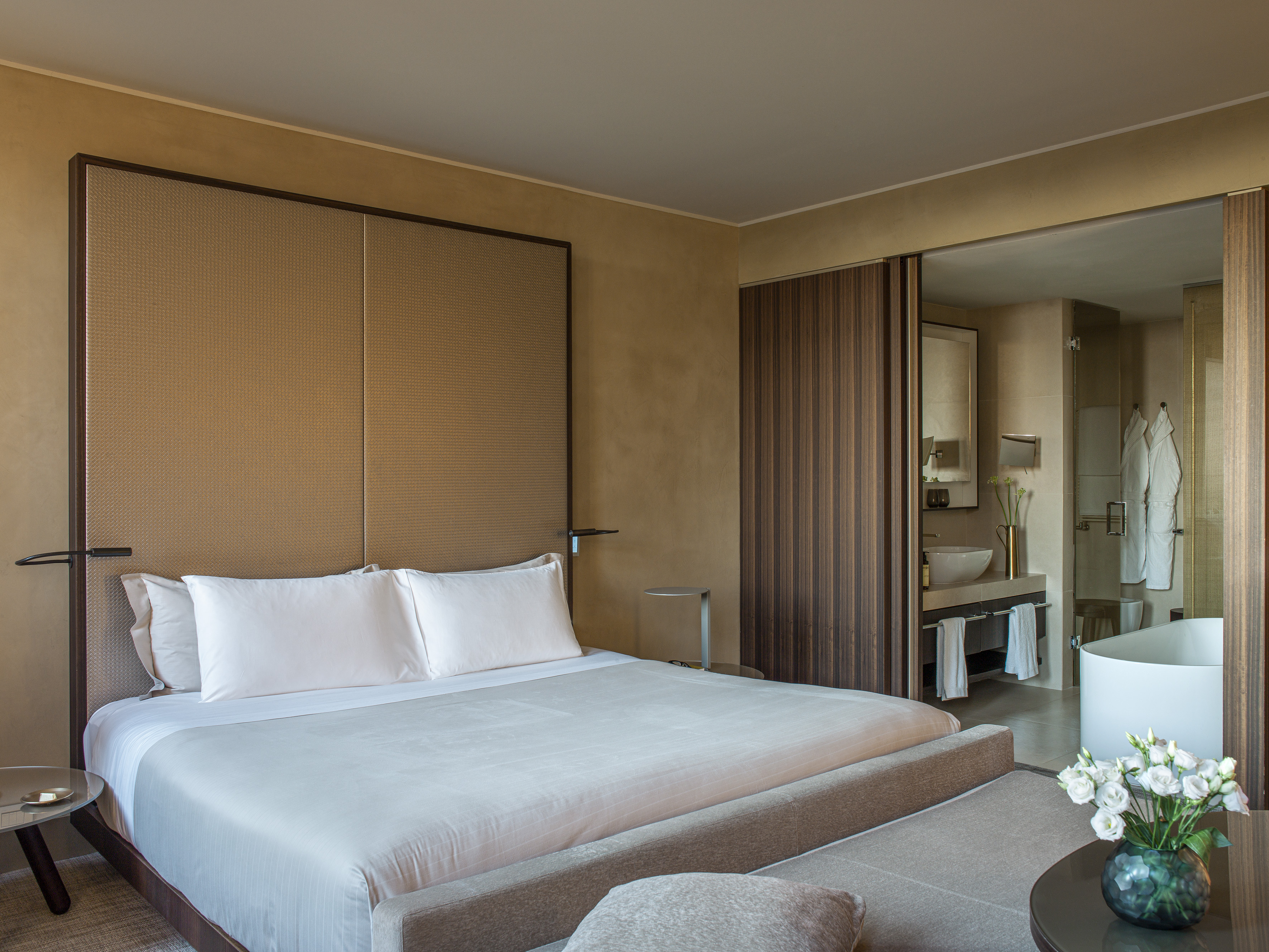 Luxury modern bedroom with king bed and open concept ensuite bathroom.