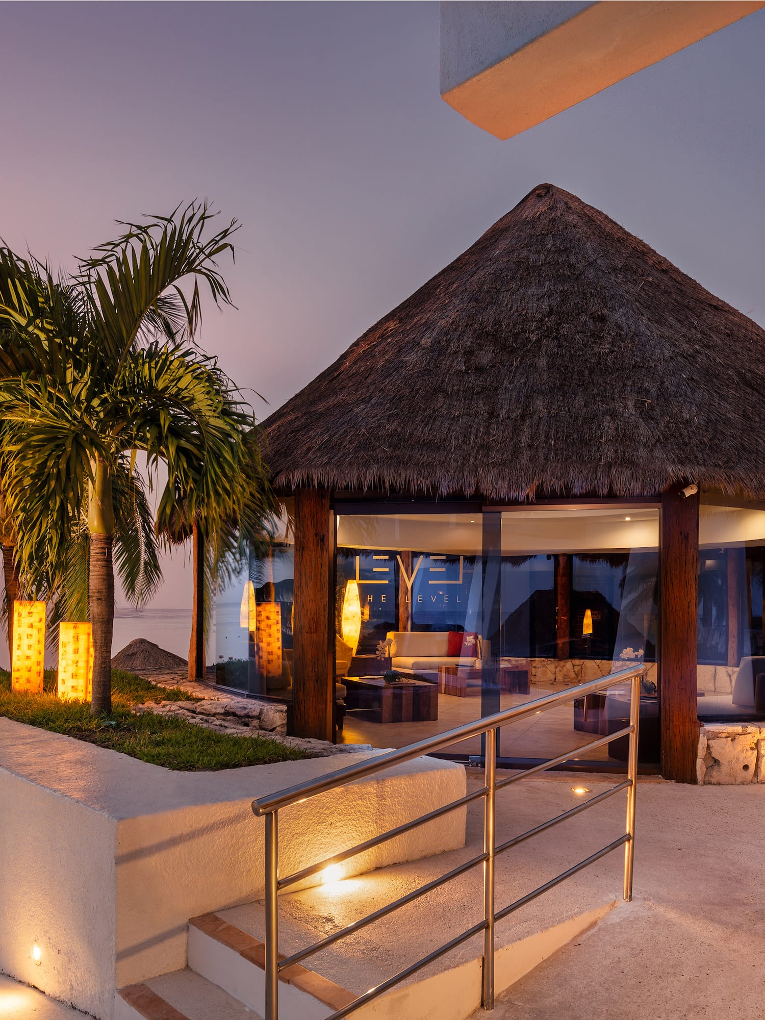a building with a thatched roof and palm trees