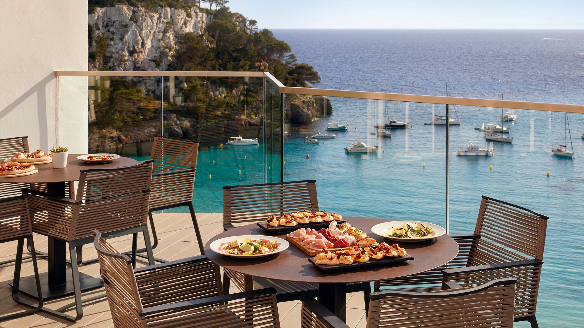 a table with food on it and chairs on a balcony overlooking water