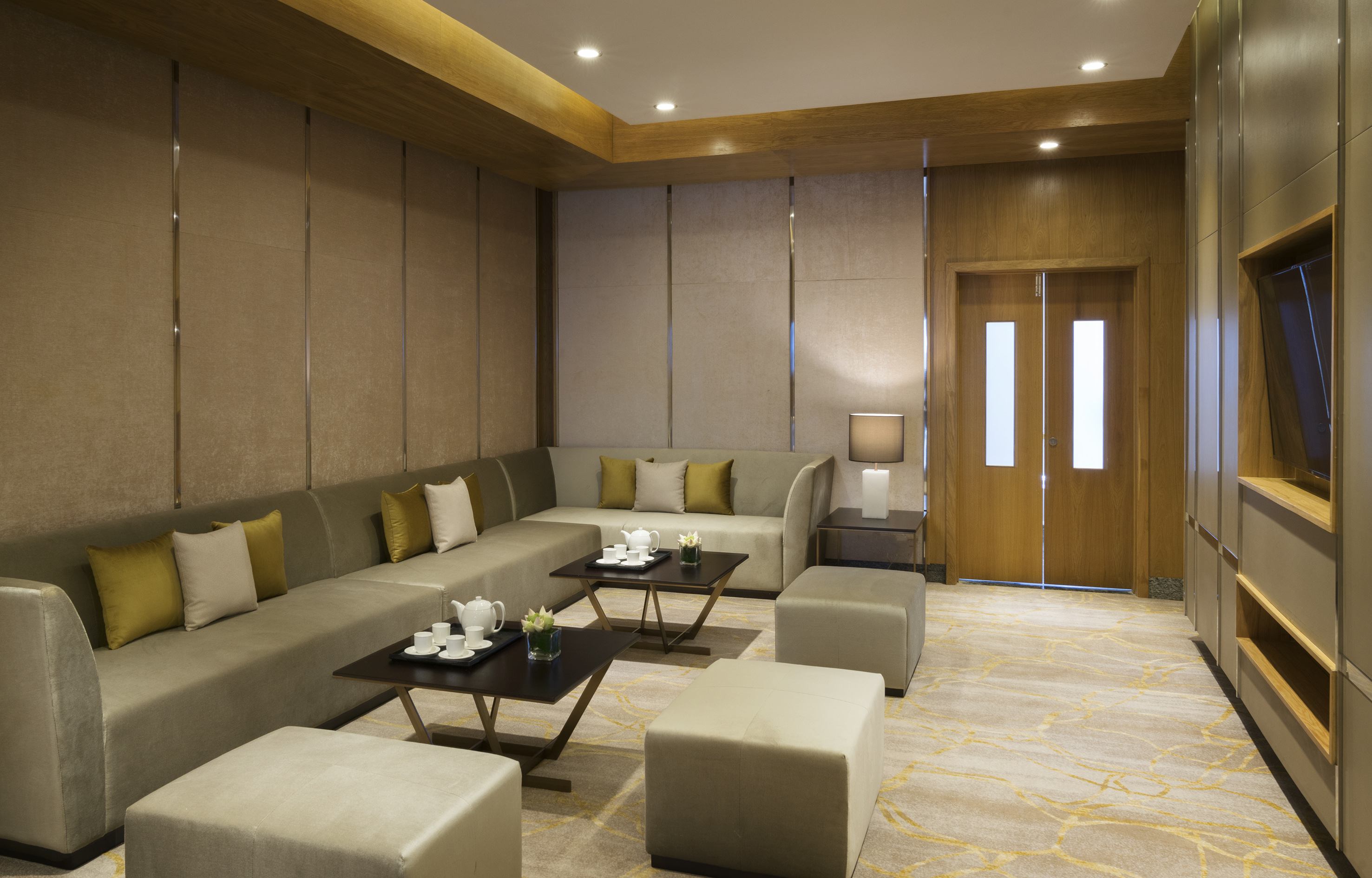 Modern luxury lounge with L-shaped sofa, coffee tables, ottomans, and neutral decor.