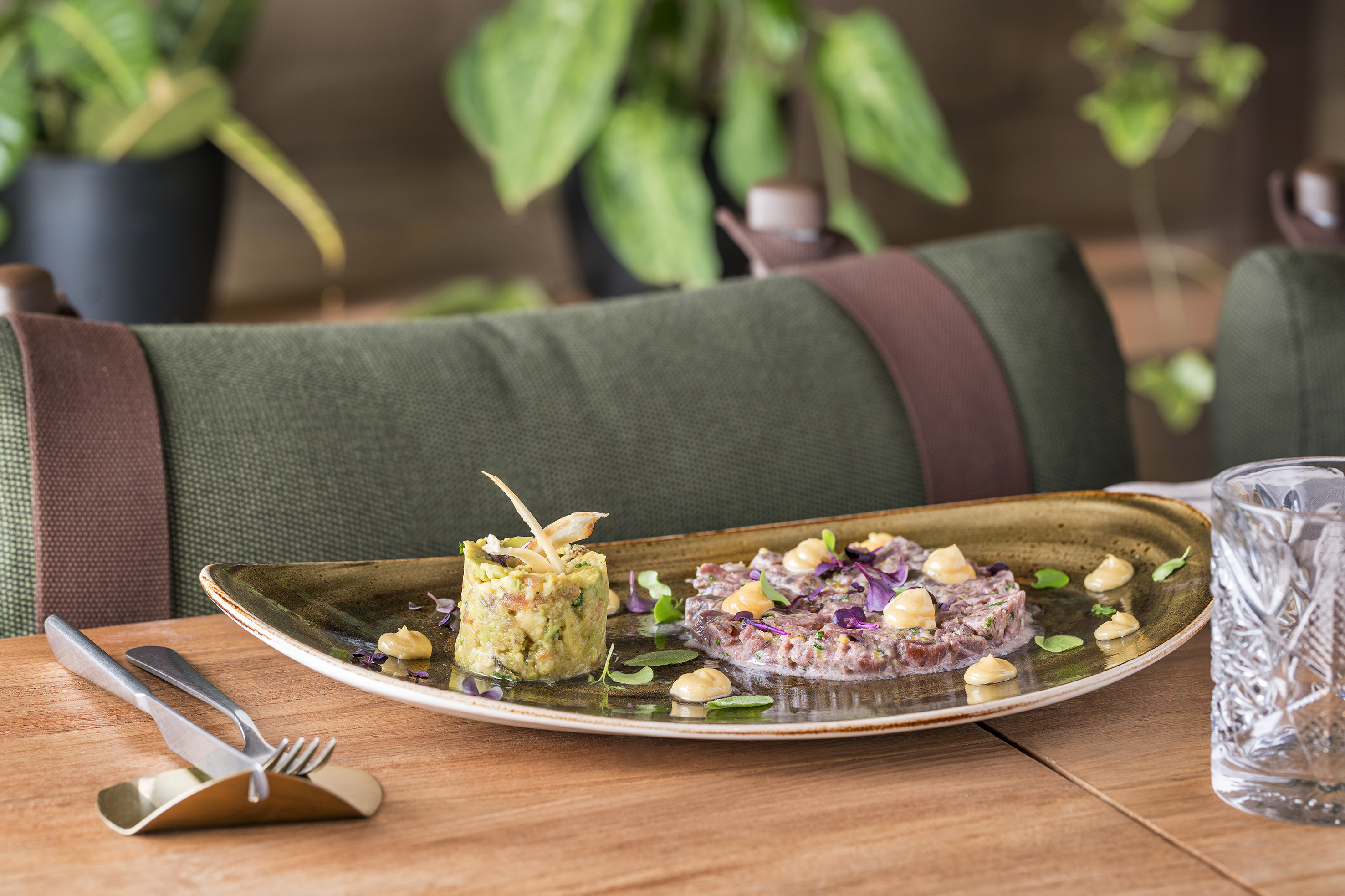 Gourmet beef and avocado tartare dish on table, restaurant setting.