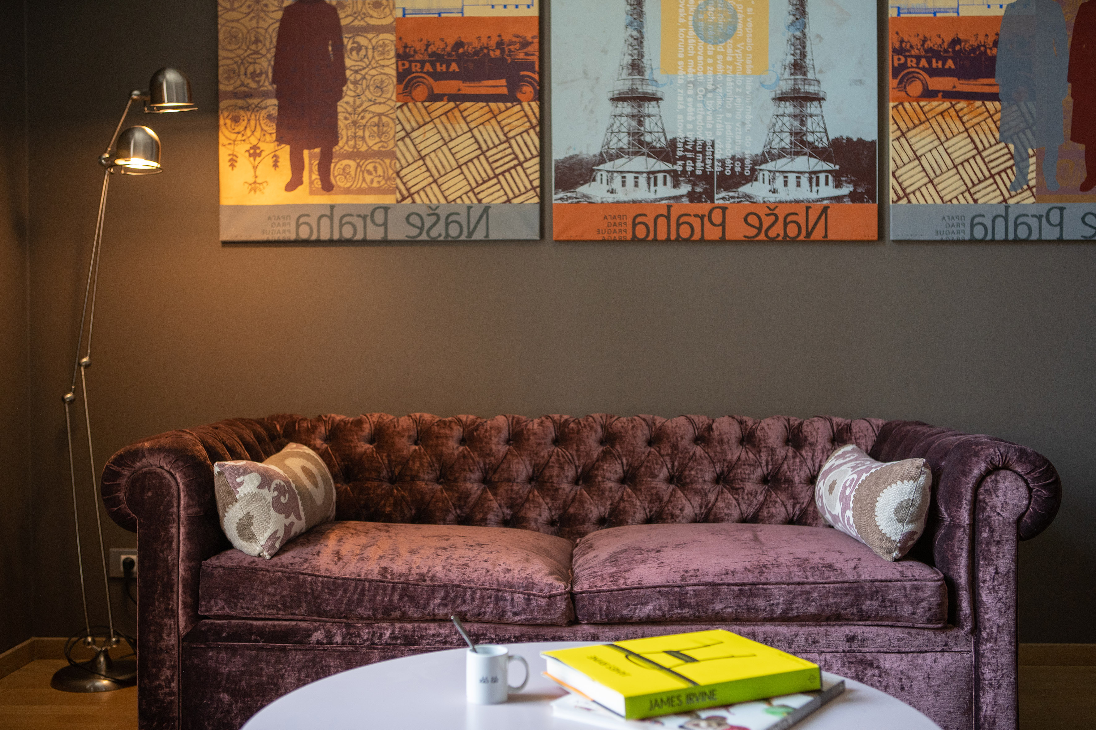 Plush purple velvet sofa in a modern living room with abstract Prague city art.