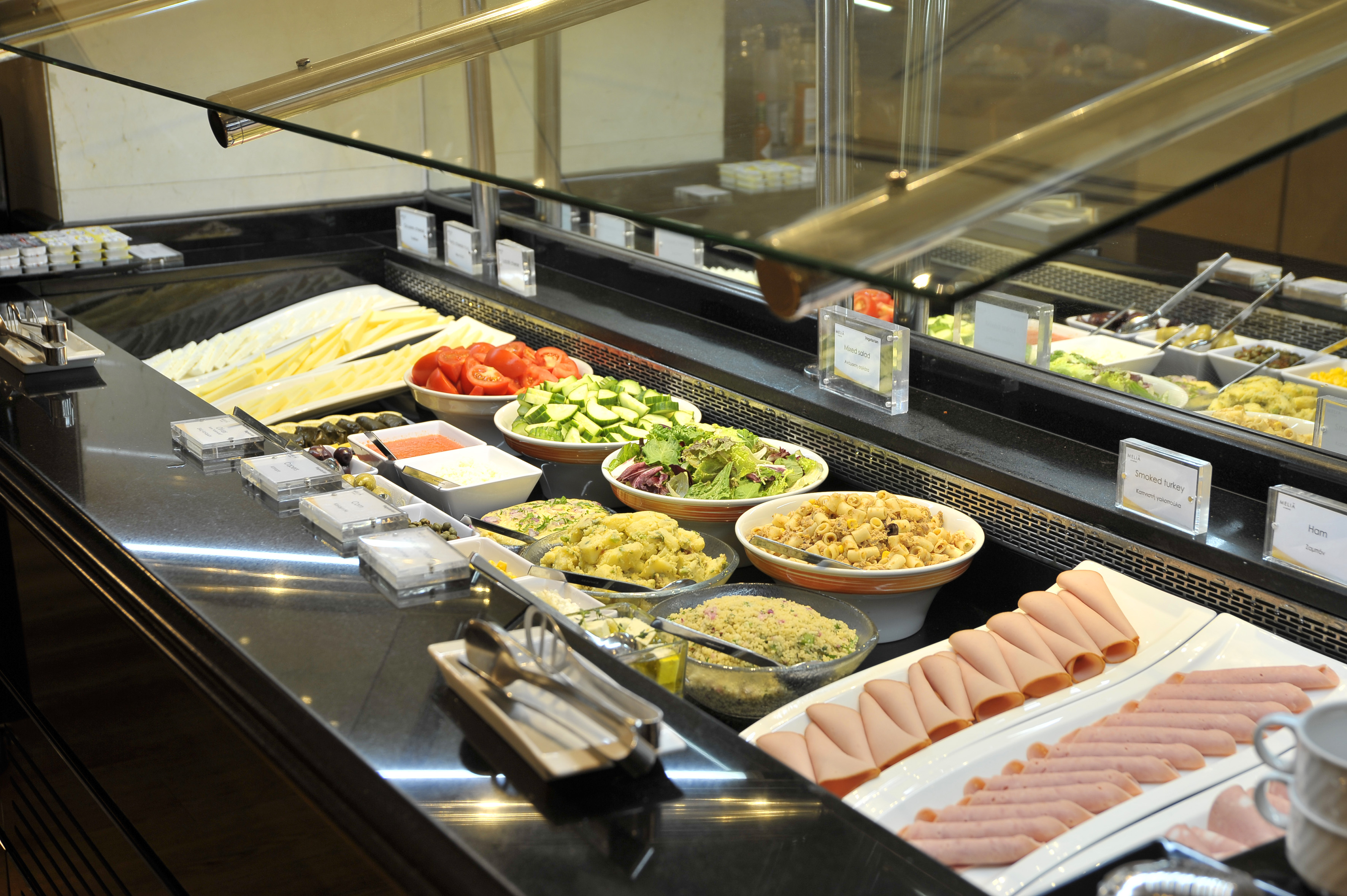 Full buffet table with salads, cheese, ham, turkey, pasta, and potato salad.