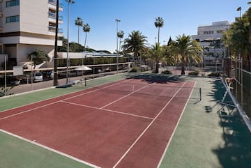 a tennis court with palm trees and buildings