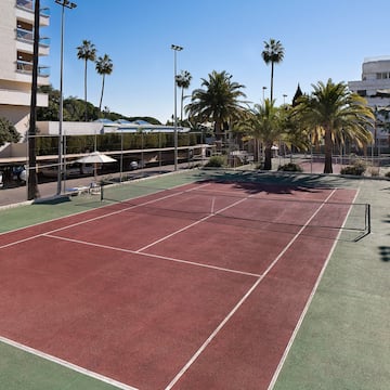 a tennis court with palm trees and buildings
