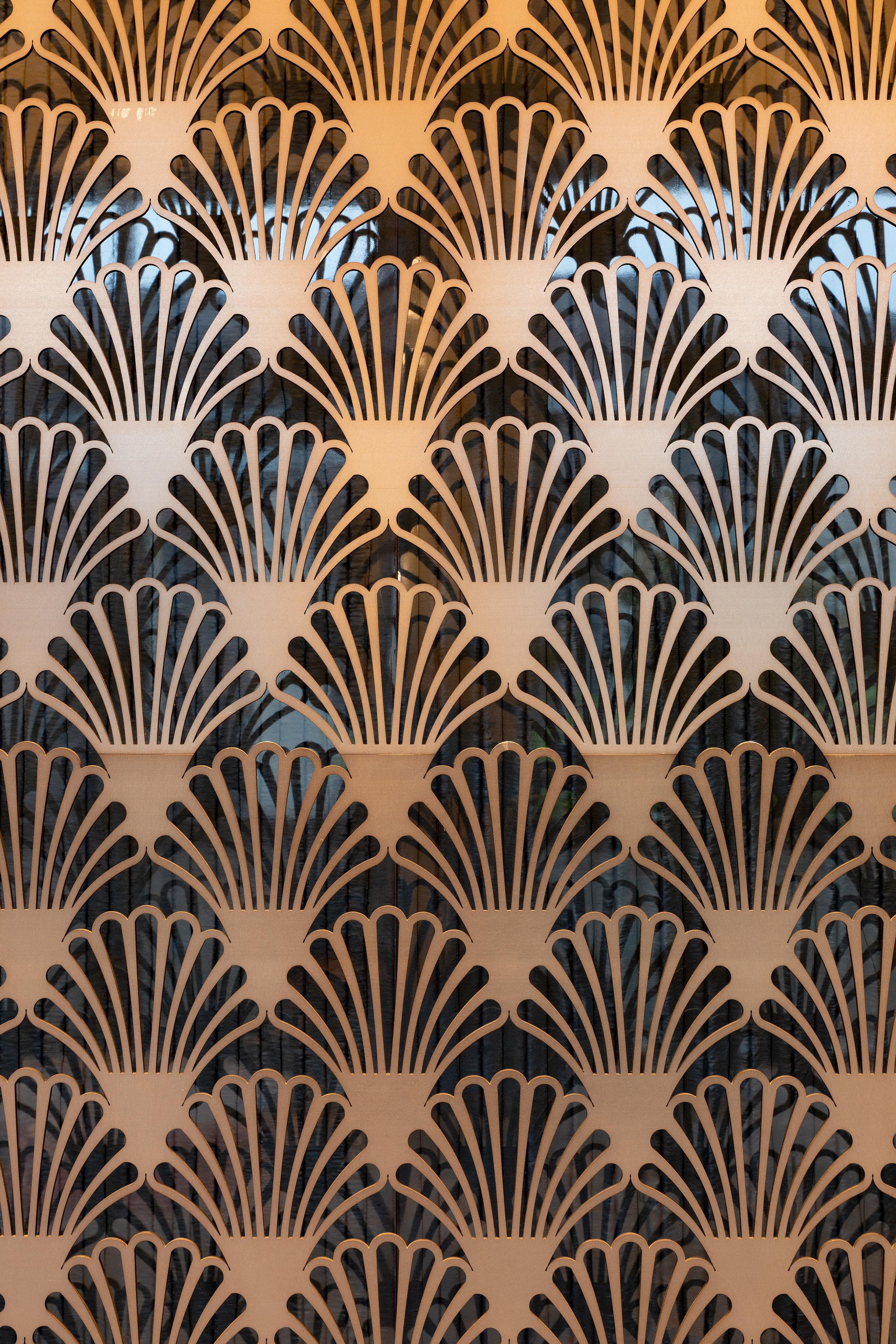 Light brown laser-cut screen with repeating Art Deco fan pattern