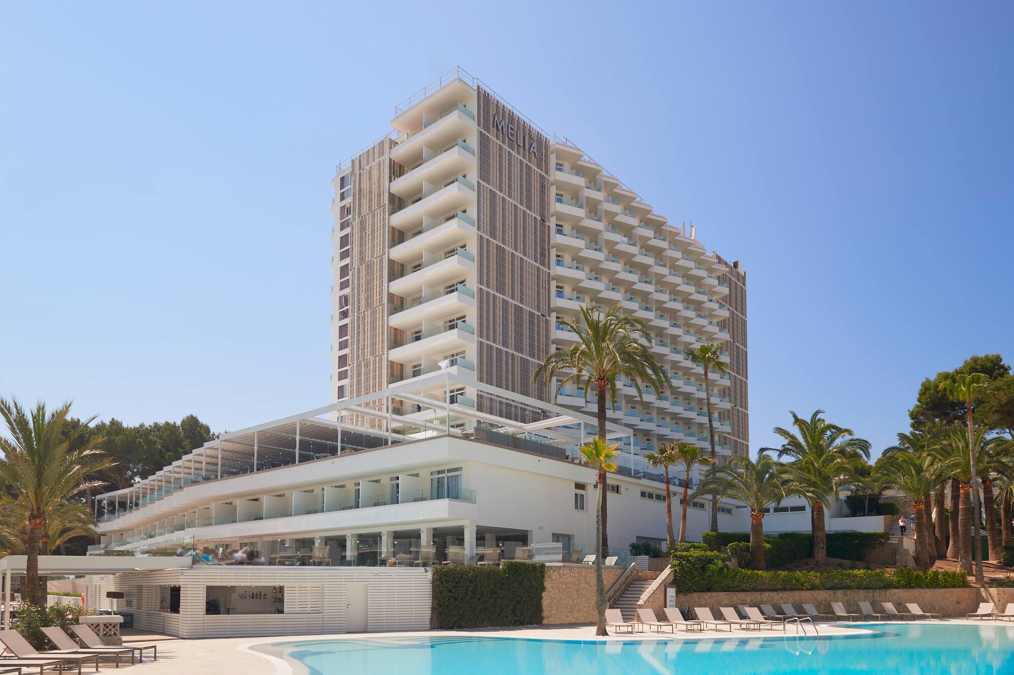 Modern Meliá hotel resort with pool, palm trees, and numerous balconies.