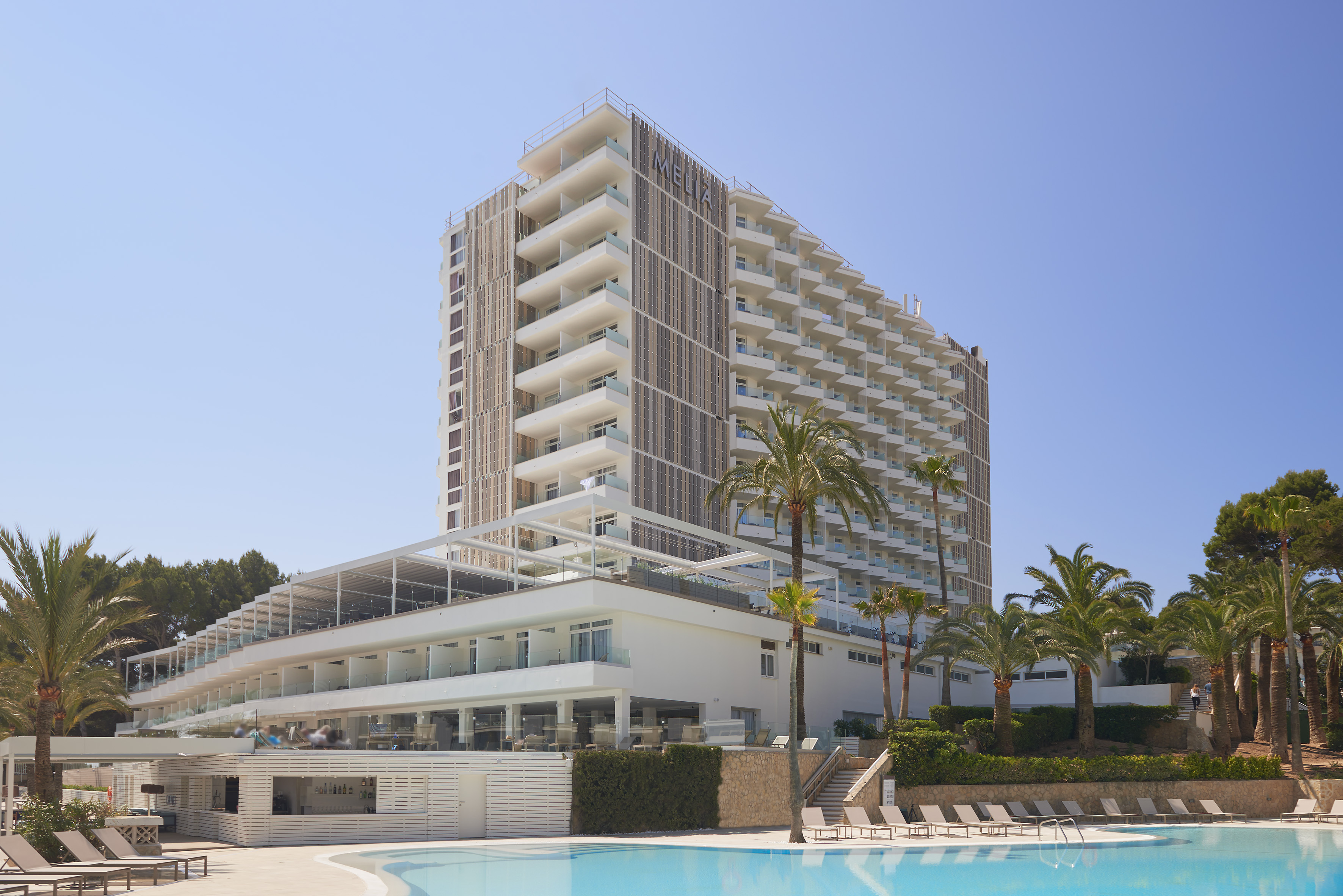 Modern Meliá hotel resort with pool, palm trees, and numerous balconies.