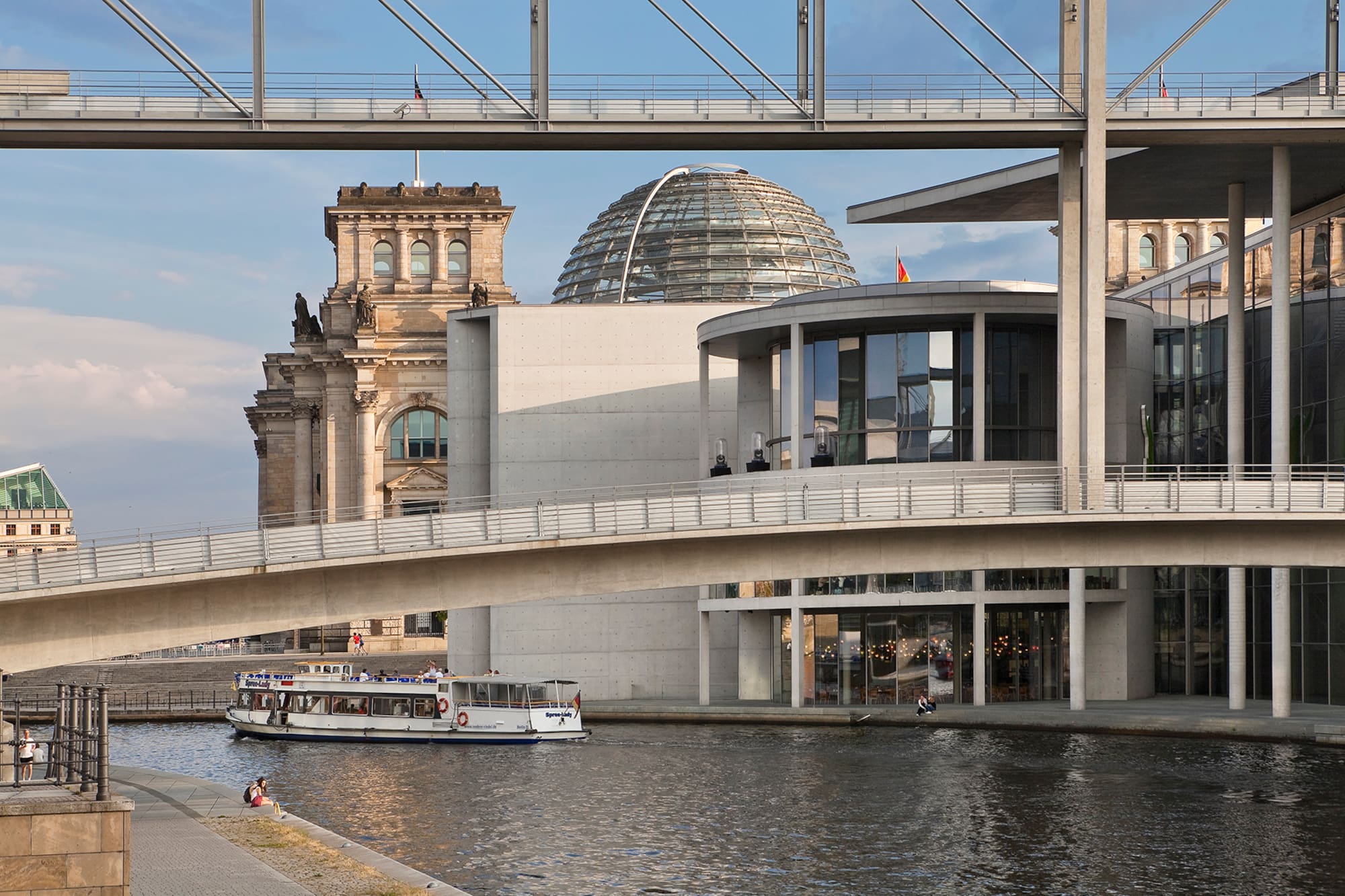 Reichstag building, modern parliament buildings, Spree River, and boat in Berlin.
