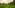a green field with mountains in the background with Li River in the background