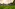 a green field with mountains in the background with Li River in the background