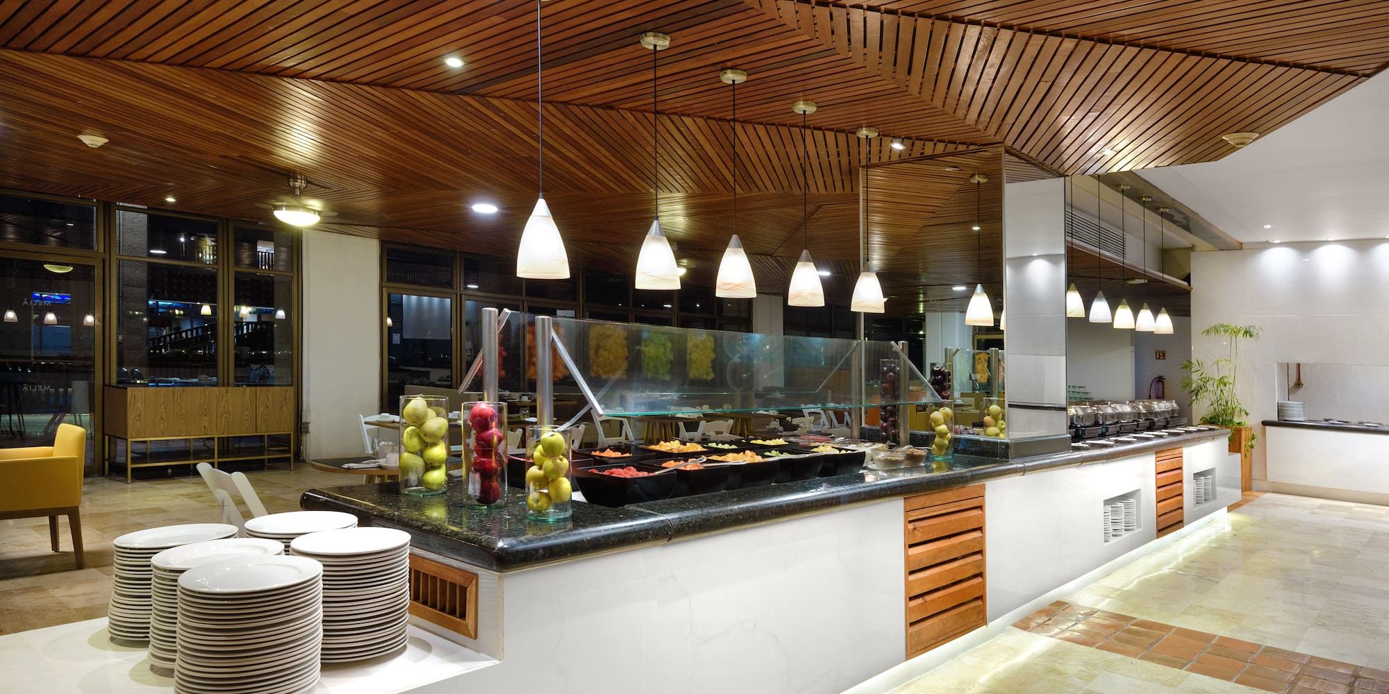 a buffet line with plates and fruit