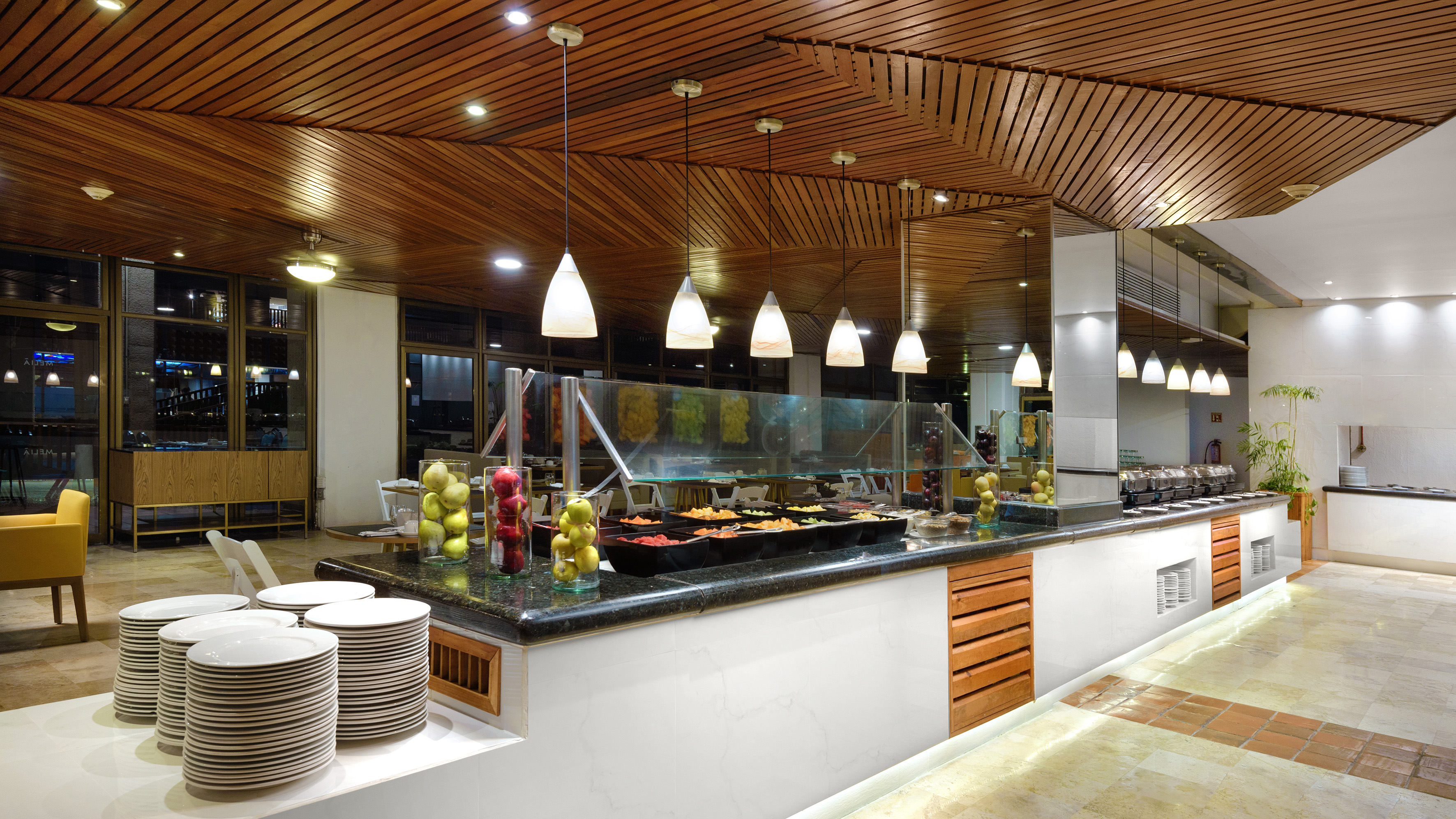 a buffet line with plates and fruit