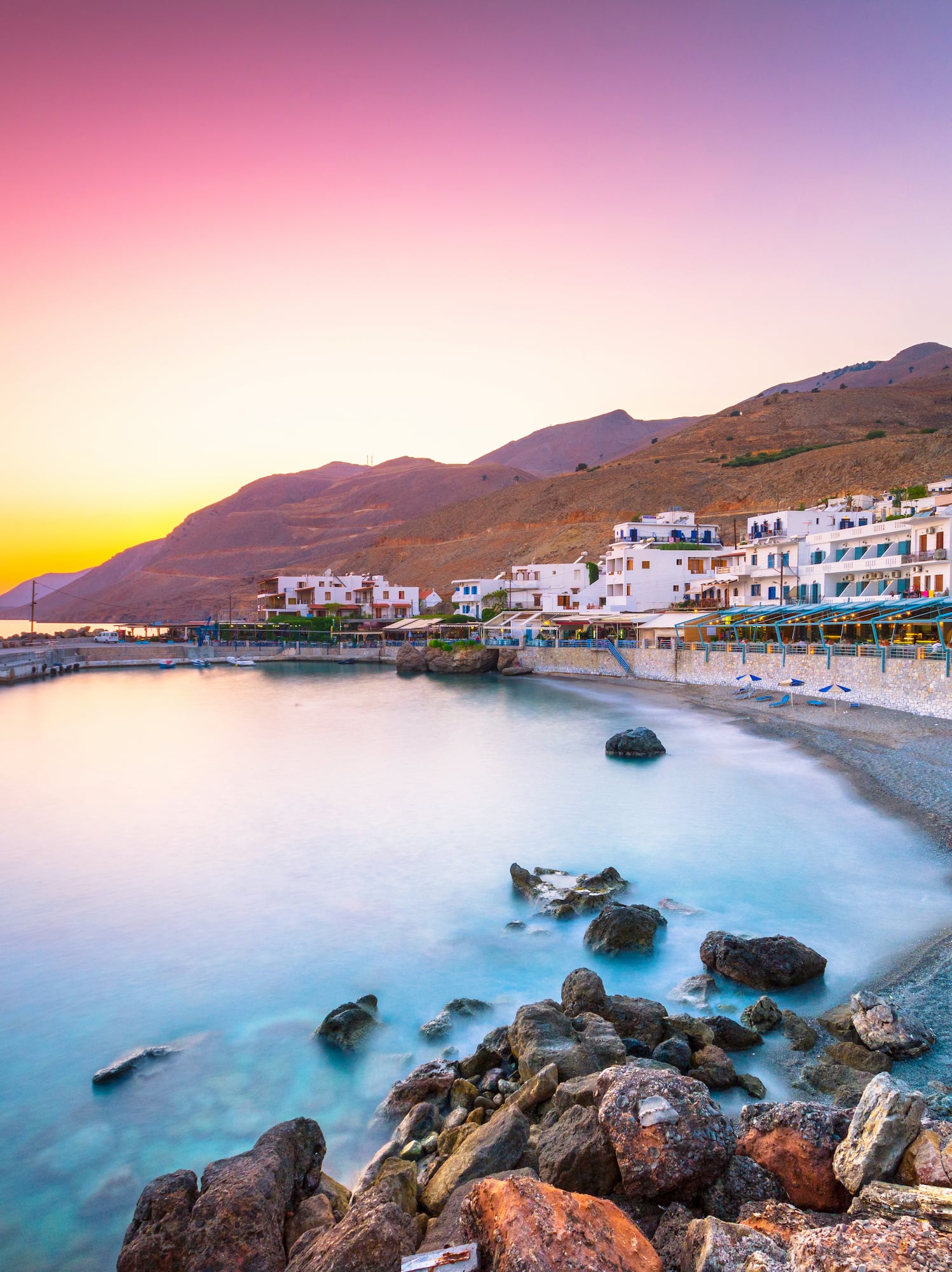 a beach with buildings and rocks