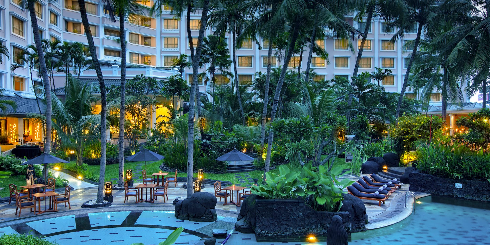 a pool with chairs and umbrellas in front of a hotel