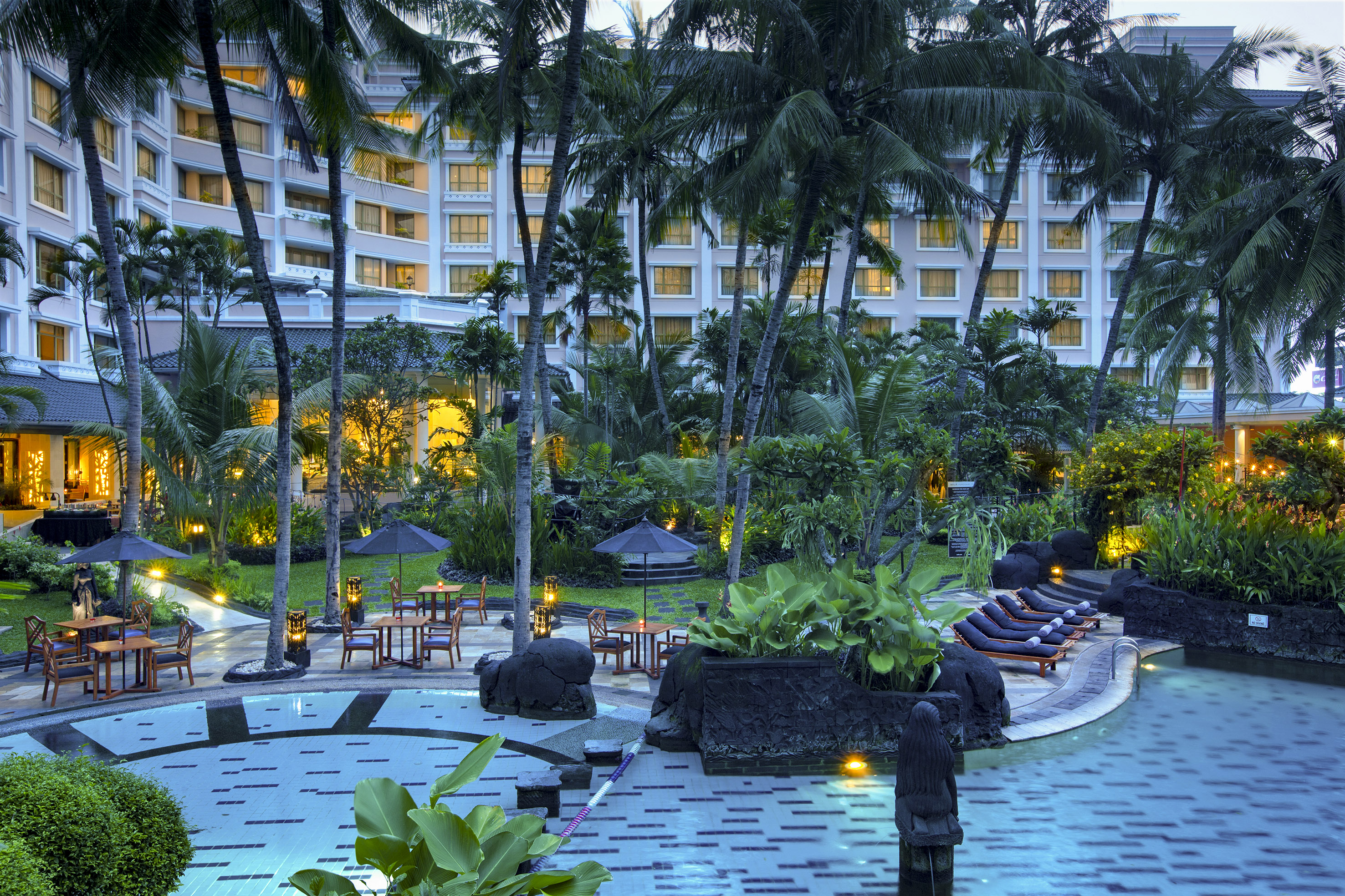 a pool with chairs and umbrellas in front of a hotel