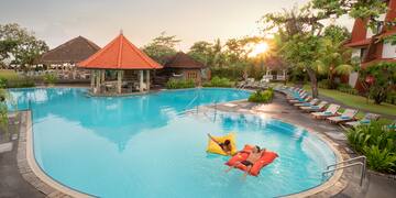 a pool with people floating on mattresses and lounge chairs
