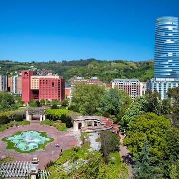 a park with a fountain and buildings in the background