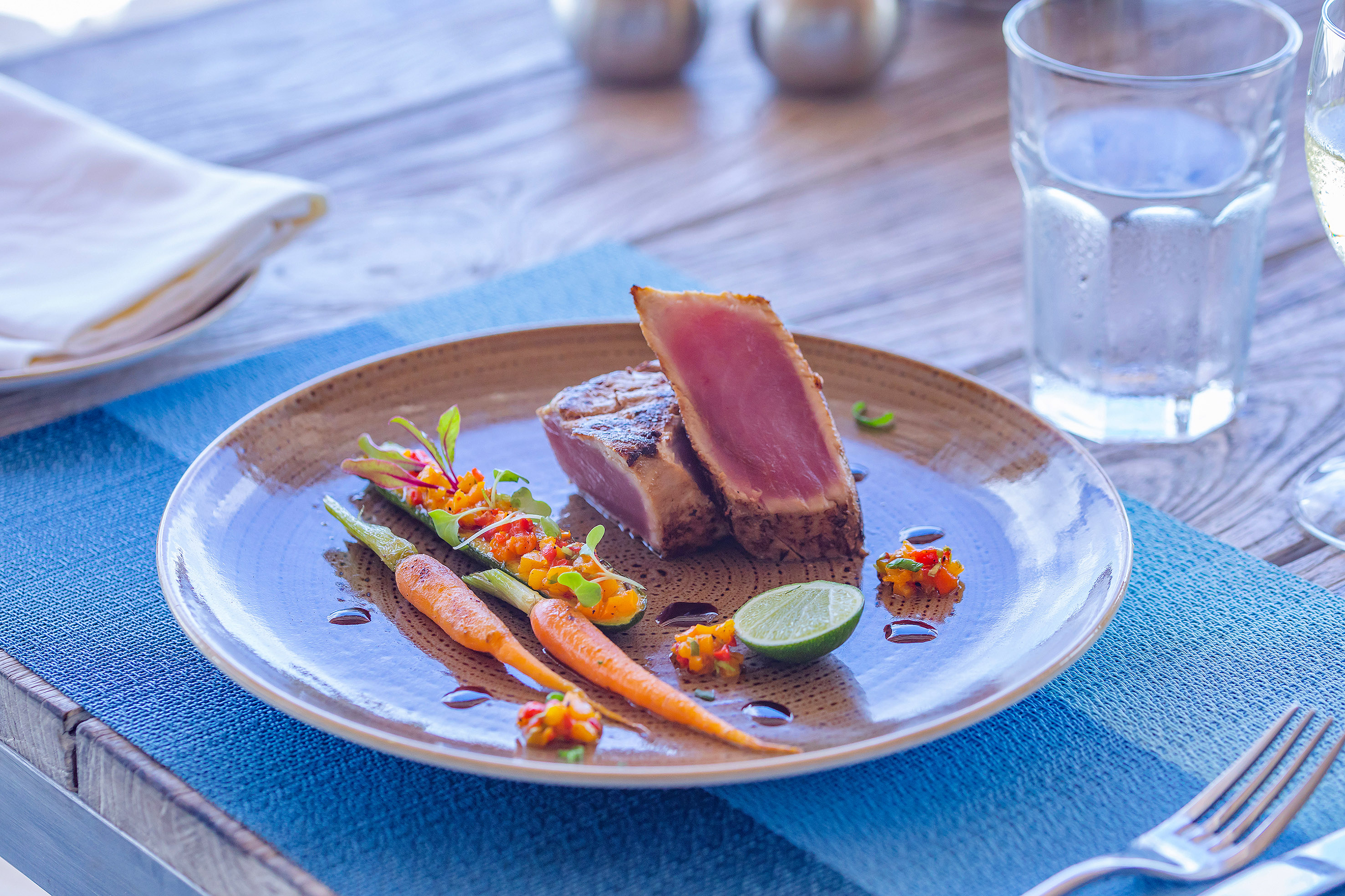 Gourmet seared ahi tuna with roasted carrots, colorful salsa, and lime.