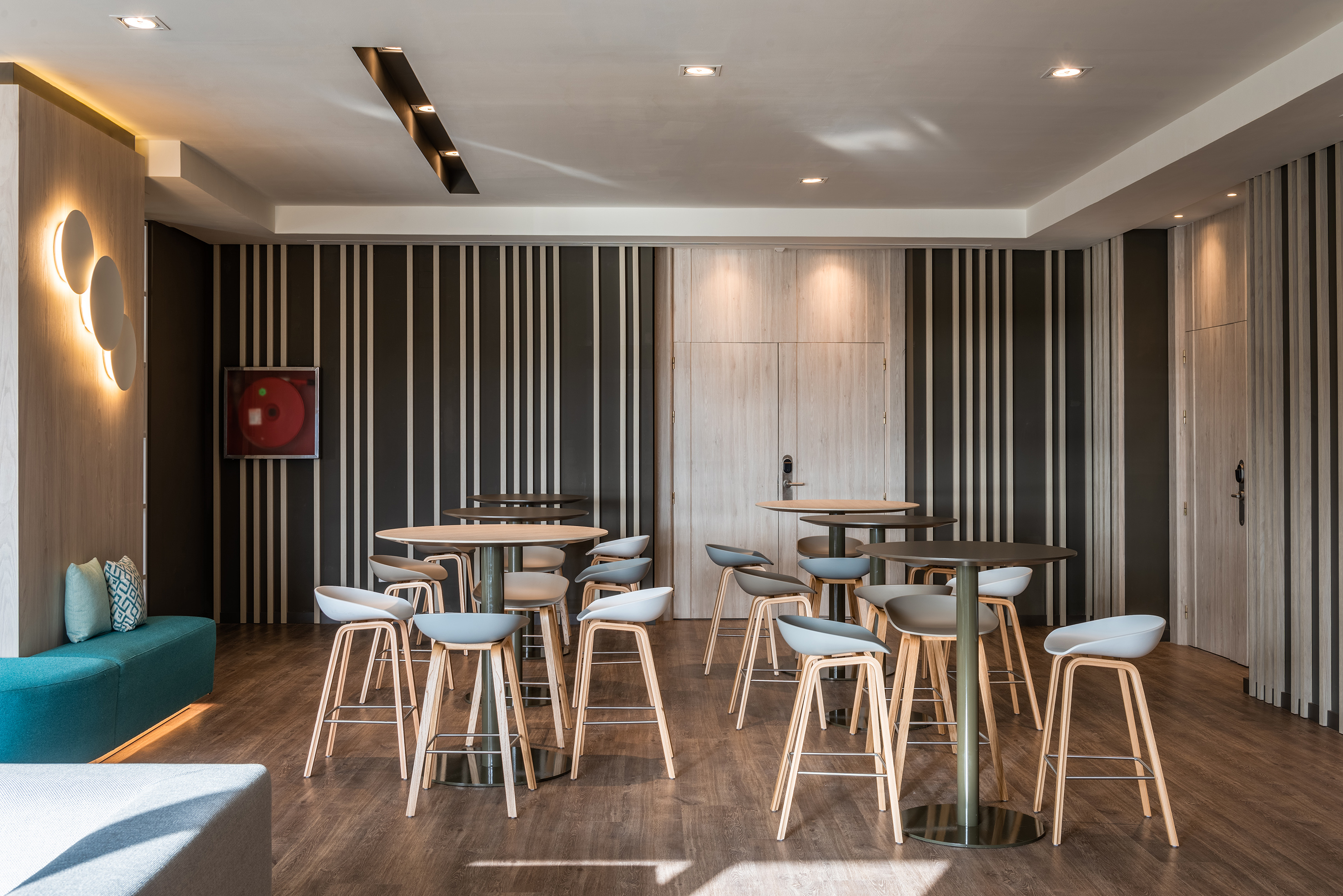 Modern lounge with high-top tables, bar stools, wood floors & striped walls.