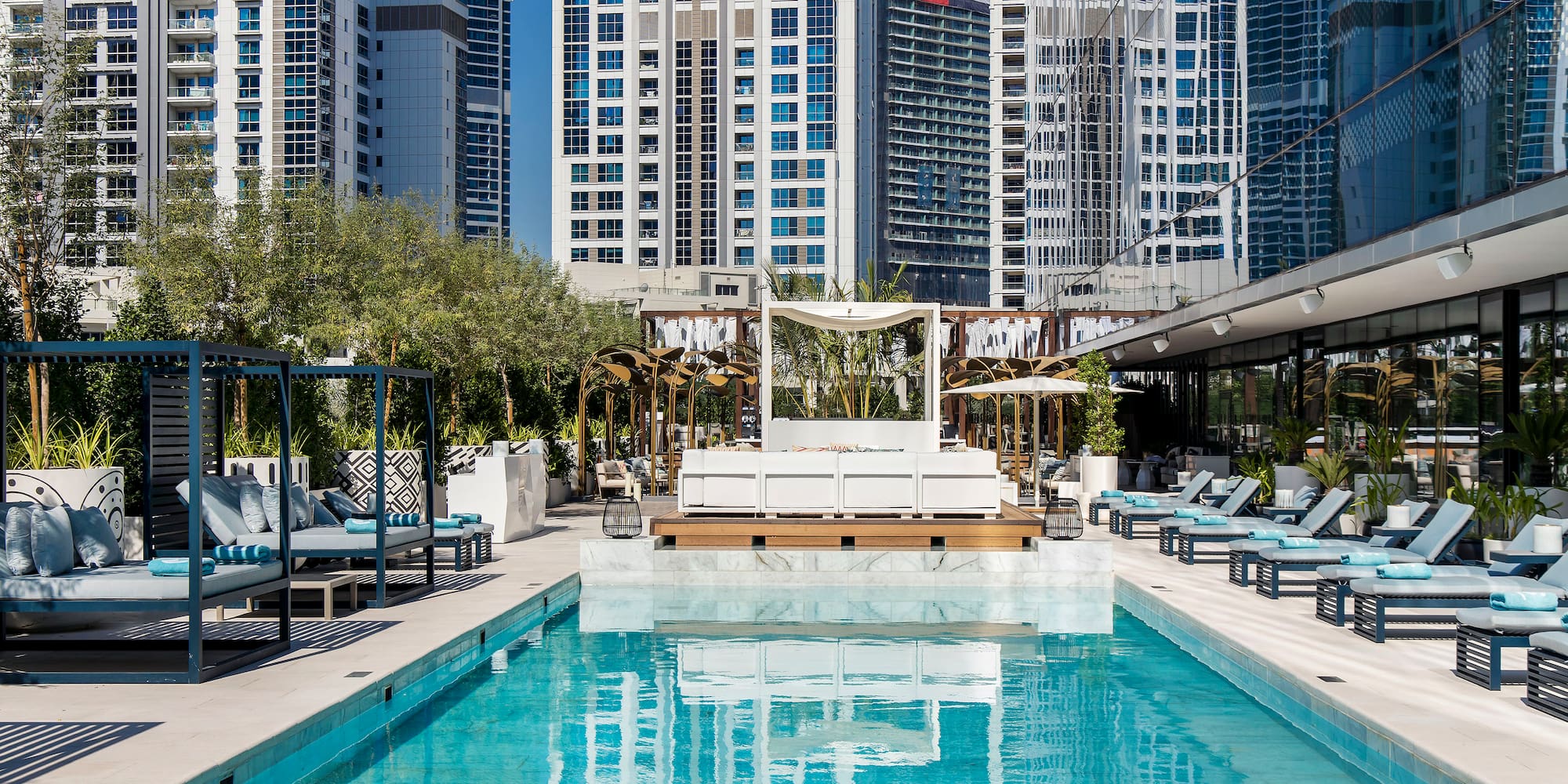 a pool with lounge chairs and trees in front of buildings