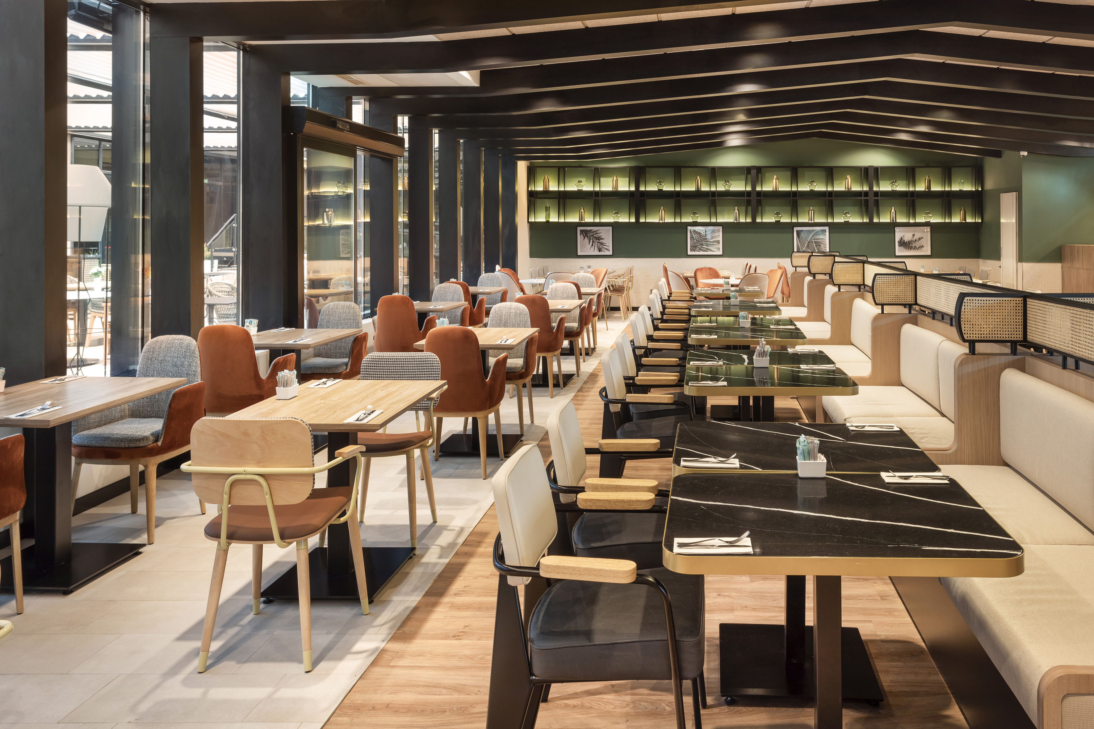 Modern restaurant dining area with wooden and dark marble tables, diverse seating.