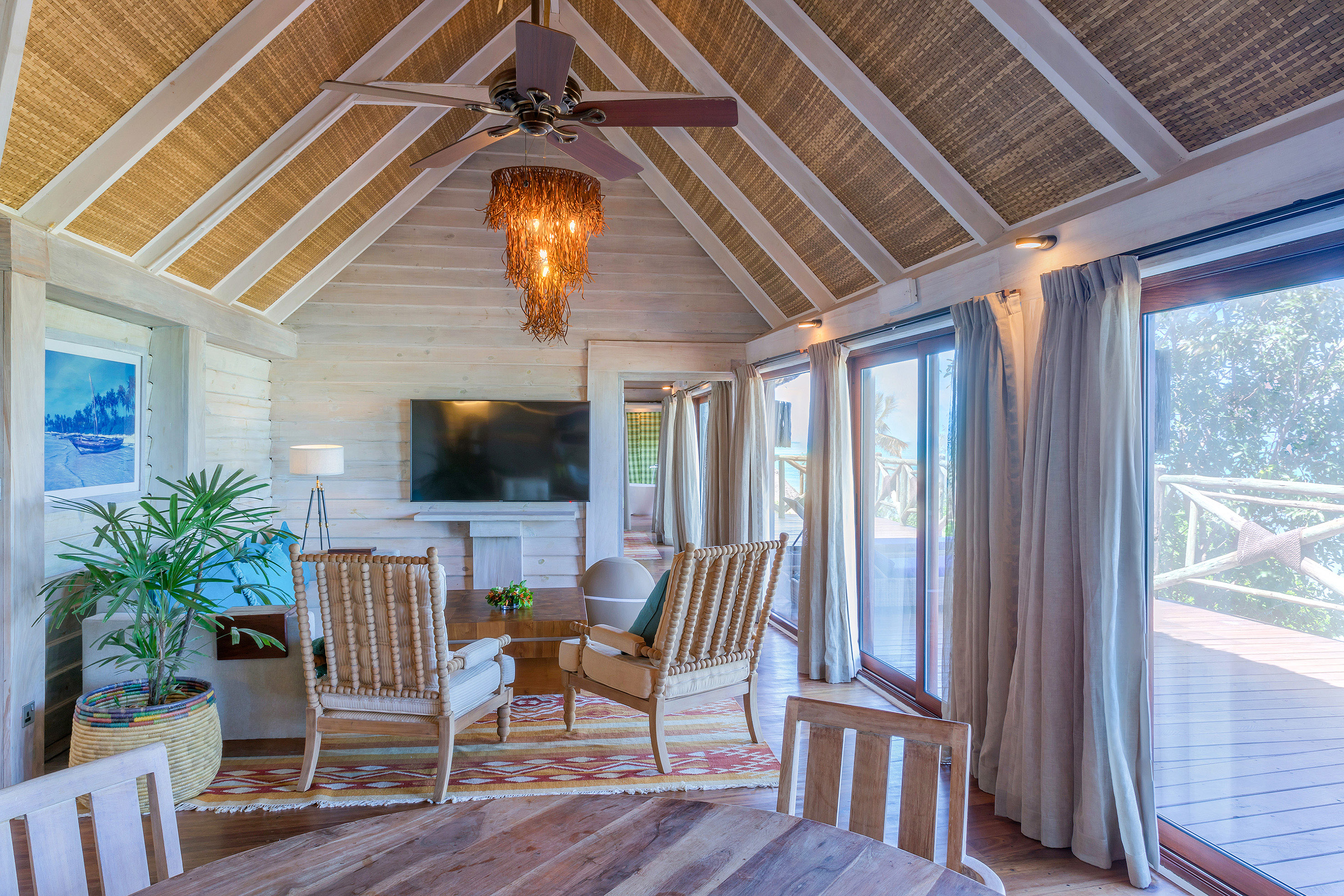 Tropical living room with vaulted woven ceiling, rustic decor, and deck.