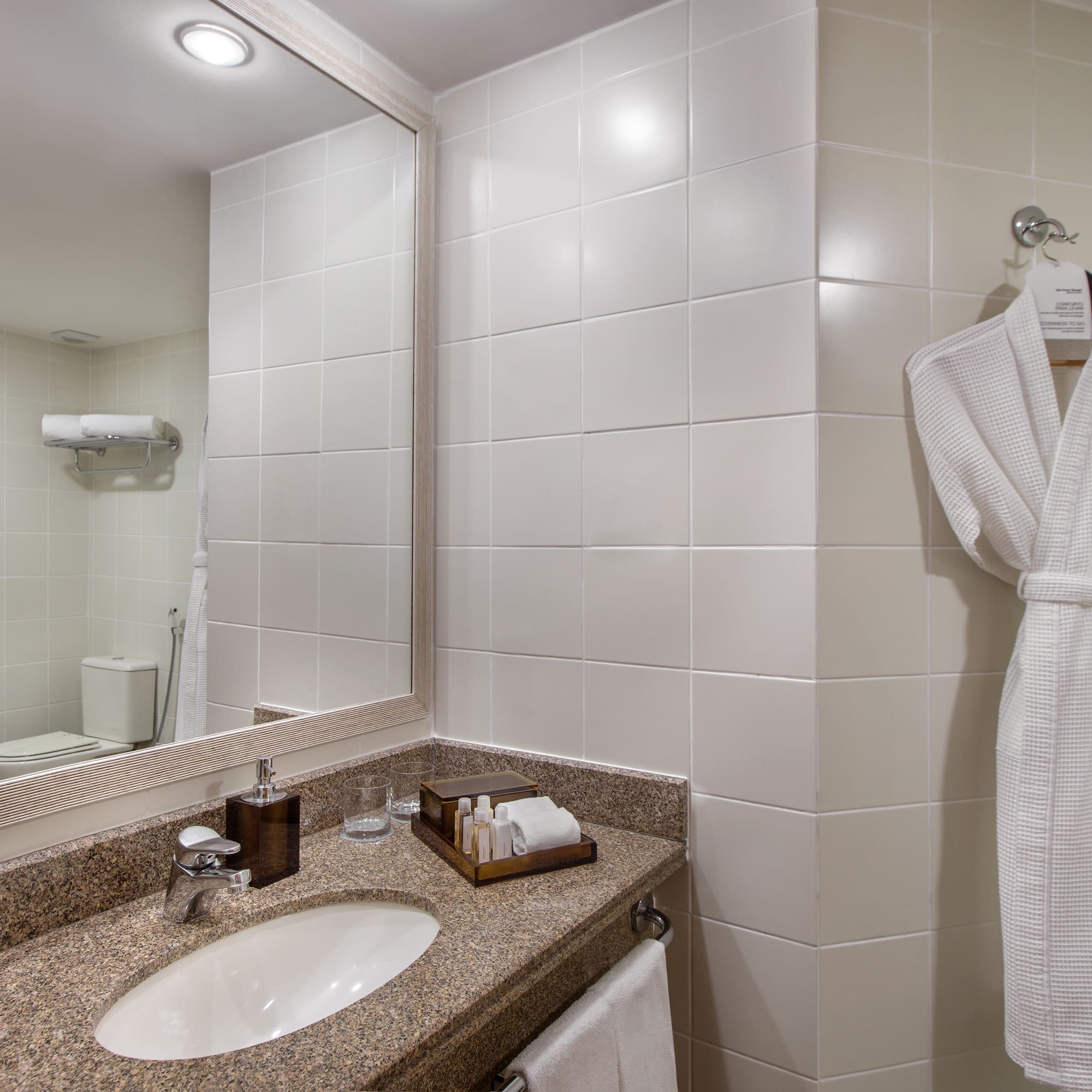 a bathroom with a white bathrobe and a mirror