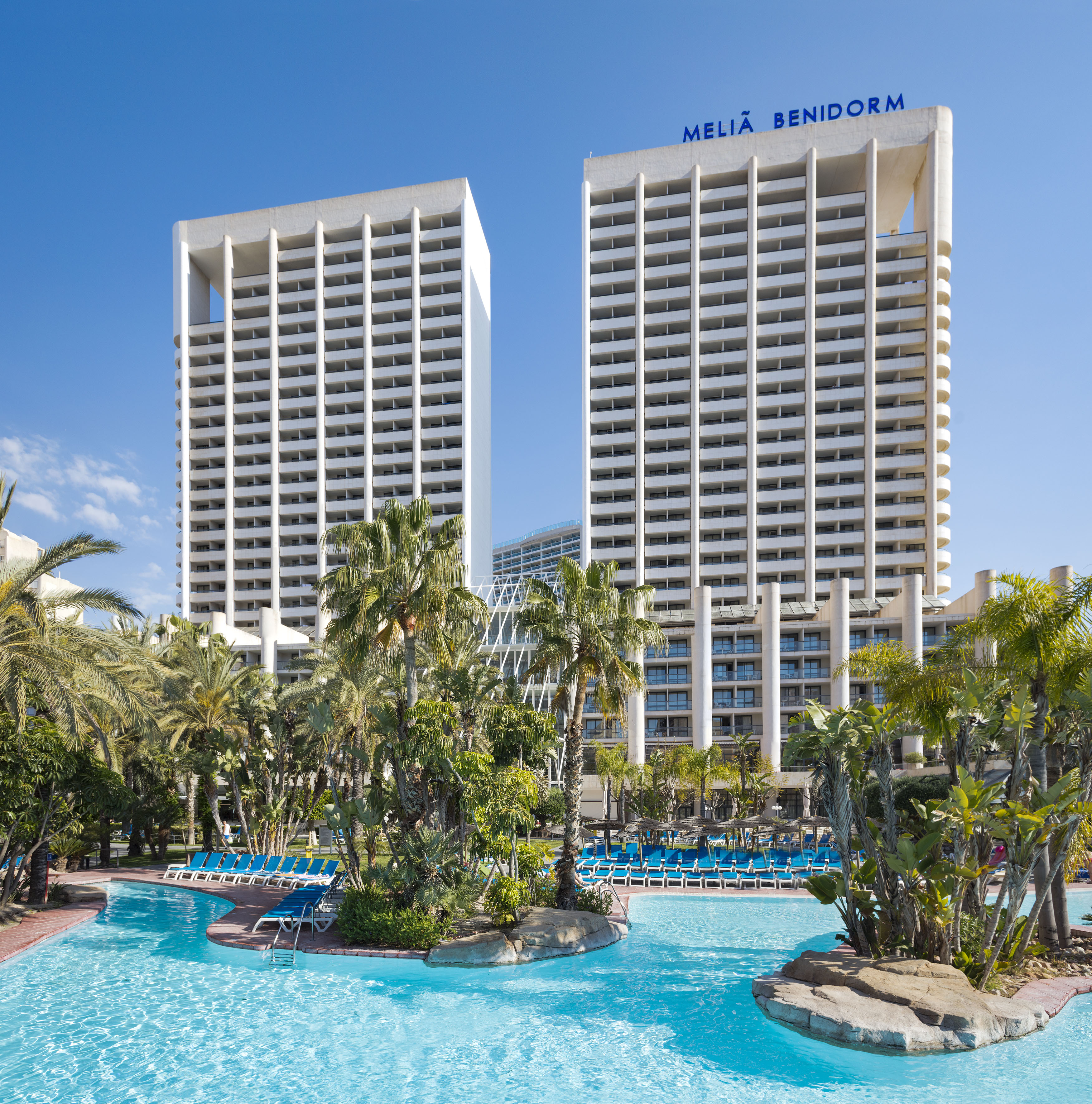 a pool with palm trees and buildings
